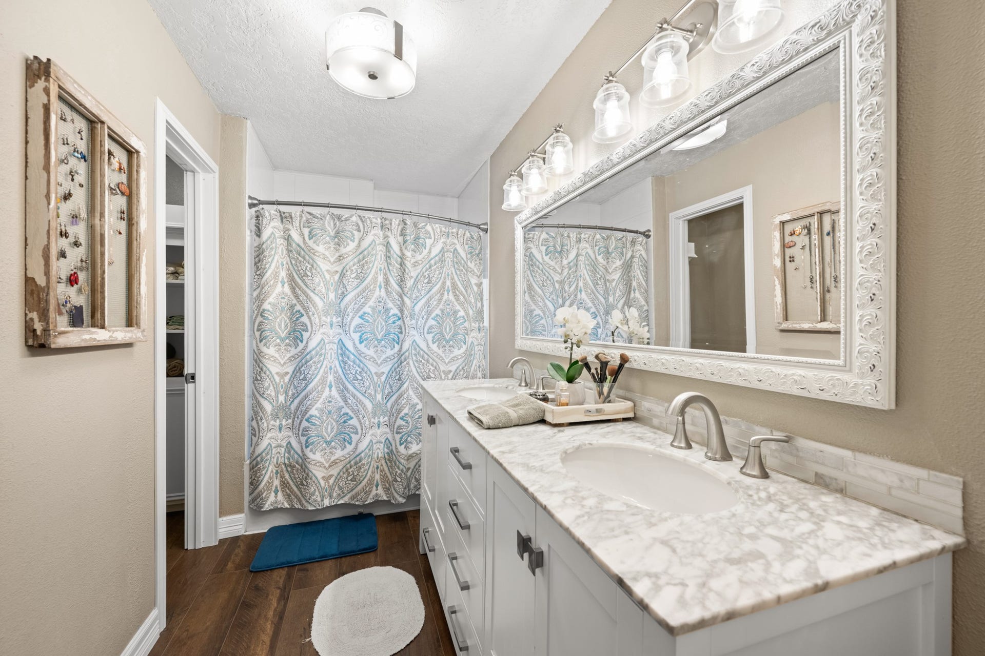 2215 Avenue Q, Santa Fe, TX 77510 The primary bathroom offers a generous double-sink vanity with stone-look countertops, decorative tile backsplash, oversized framed mirror, and a tub/shower combination with access to a walk-in closet.