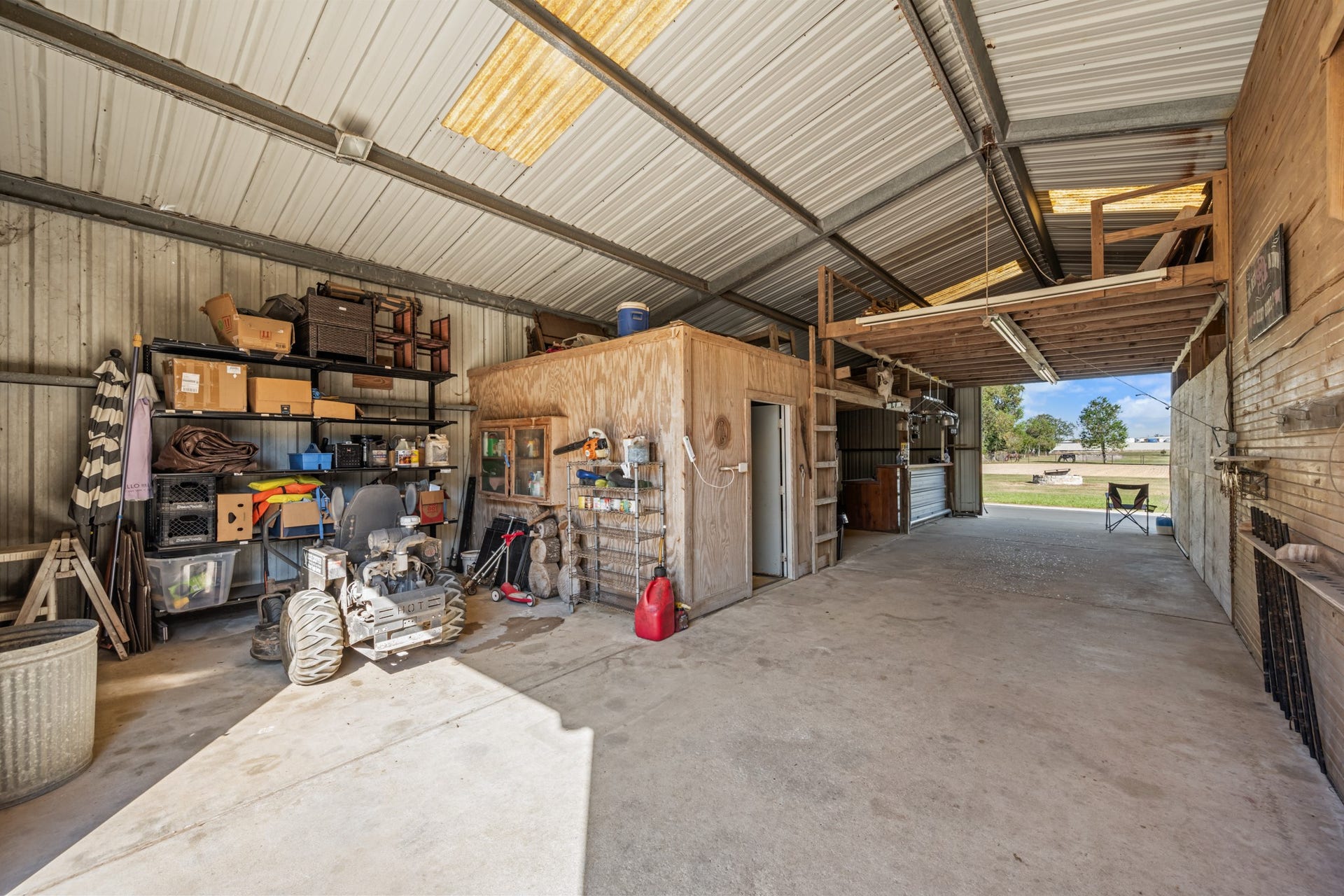 2215 Avenue Q, Santa Fe, TX 77510 Versatile covered workspace featuring concrete floors, built-in shelving, enclosed storage, overhead loft space, and easy access to the surrounding property.