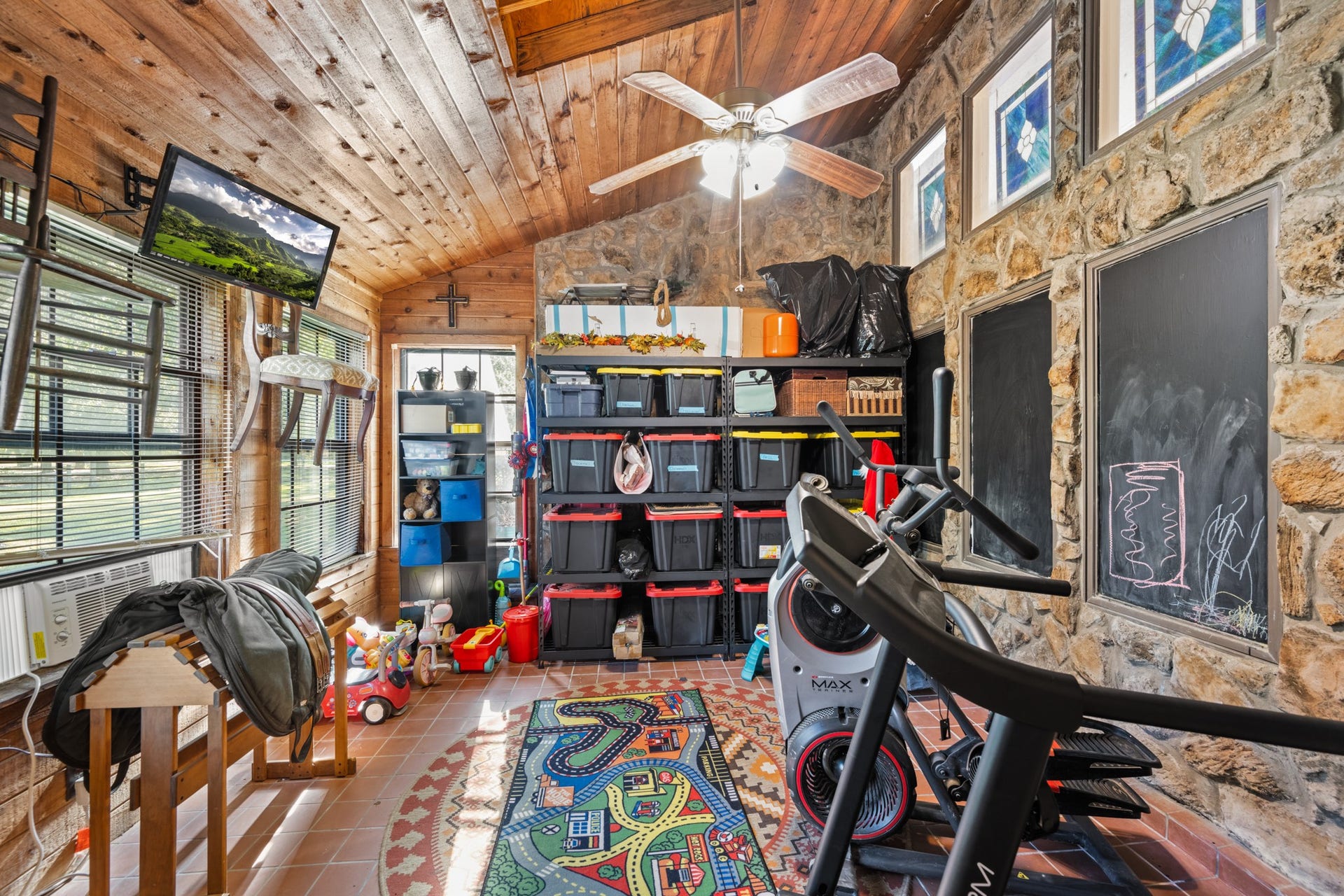 2215 Avenue Q, Santa Fe, TX 77510 Versatile bonus space showcases a vaulted wood-plank ceiling, exposed stone walls, abundant windows, and tile flooring. Ideal for a home gym, hobby room, playroom, or additional flex space.
