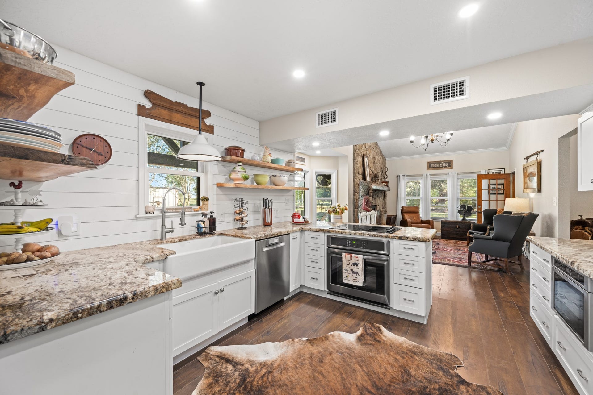 2215 Avenue Q, Santa Fe, TX 77510 Rustic farmhouse details take center stage with white shiplap walls, natural wood shelving, a farmhouse sink, and warm wood-look flooring.