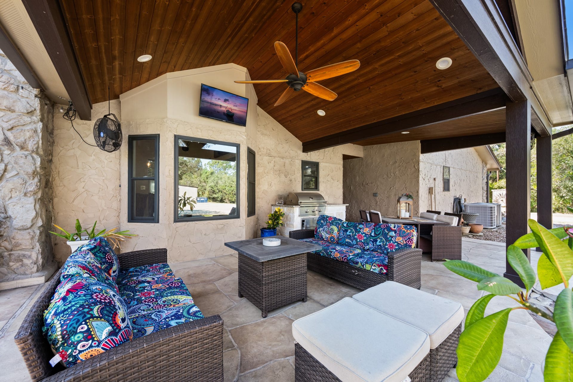 2215 Avenue Q, Santa Fe, TX 77510 Enjoy outdoor living beneath a spacious covered patio featuring a beautiful wood-plank ceiling, exposed beams, ceiling fan, comfortable seating area, and built-in grilling station. An inviting extension of the home, perfect for relaxing or entertaining.