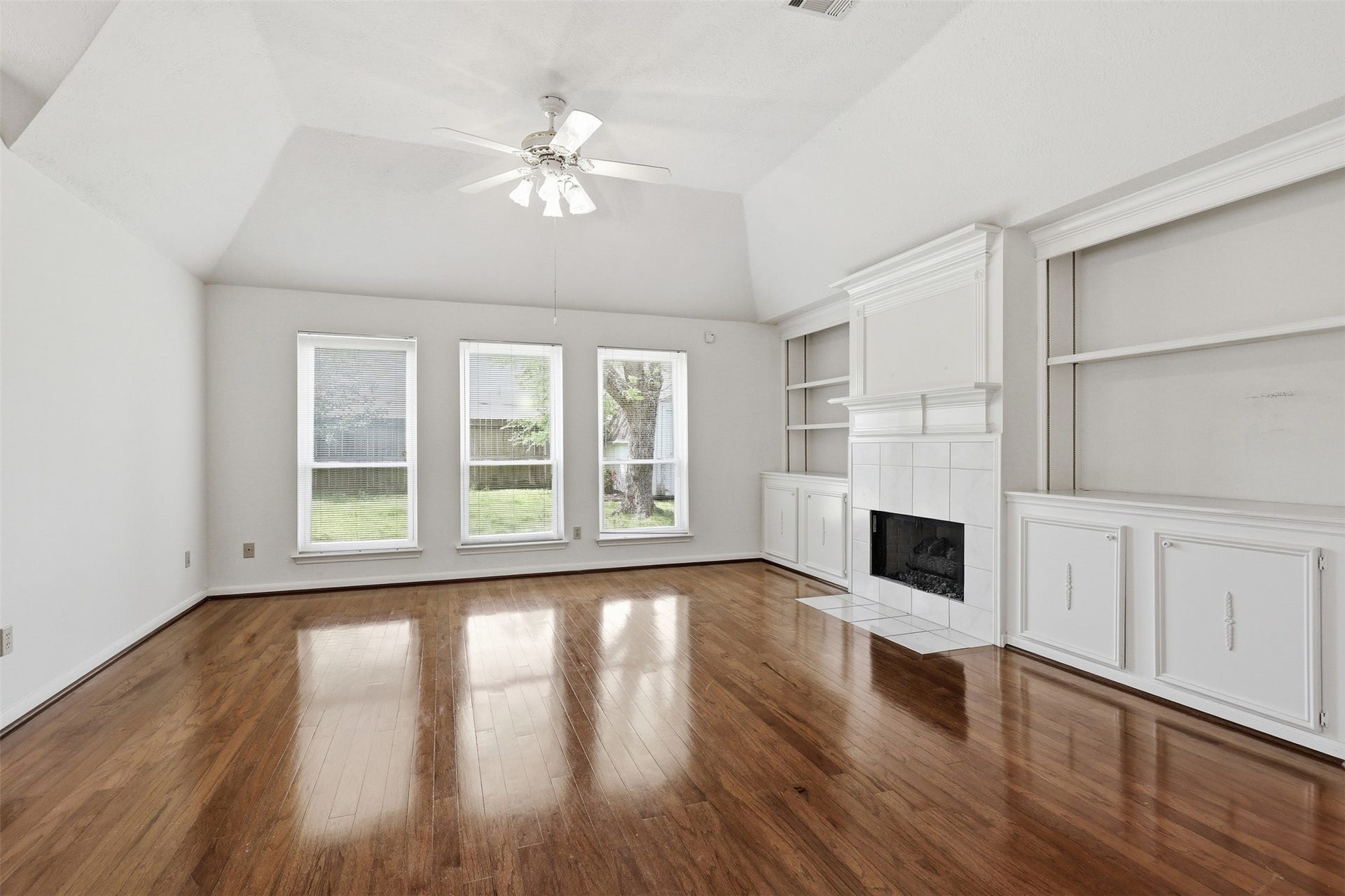 10707 Crestfield Court, Houston, TX 77070 A warm, spacious gathering area featuring polished wood floors, vaulted ceiling, and a classic fireplace with built-ins.
