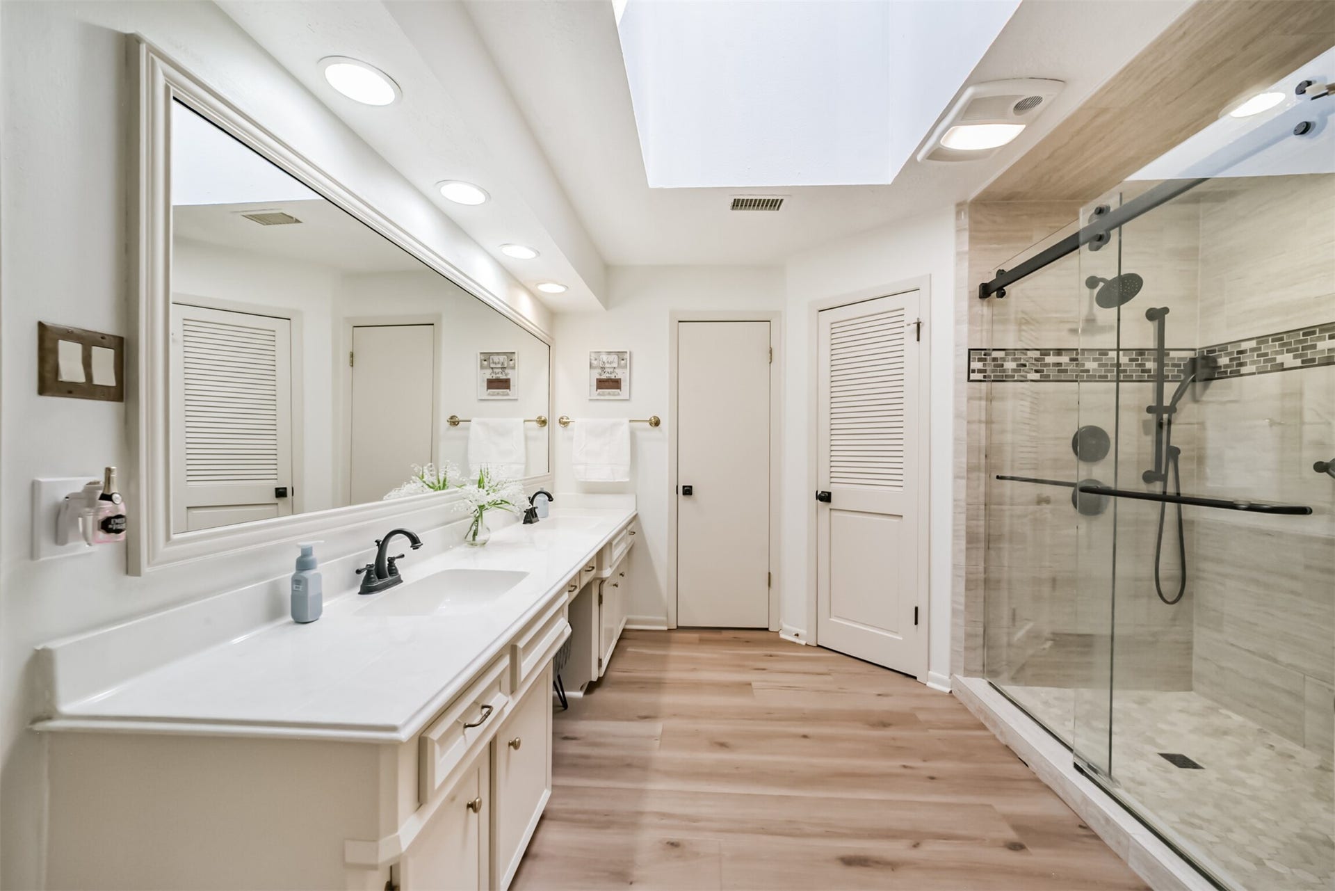 7618 Hurst Forest Drive, Humble, TX 77346 Enjoy room to spread out during your morning routine with generous vanity space, ample cabinetry, and a large mirror. The roomy glass shower and natural light from above create an inviting place to begin and end the day.