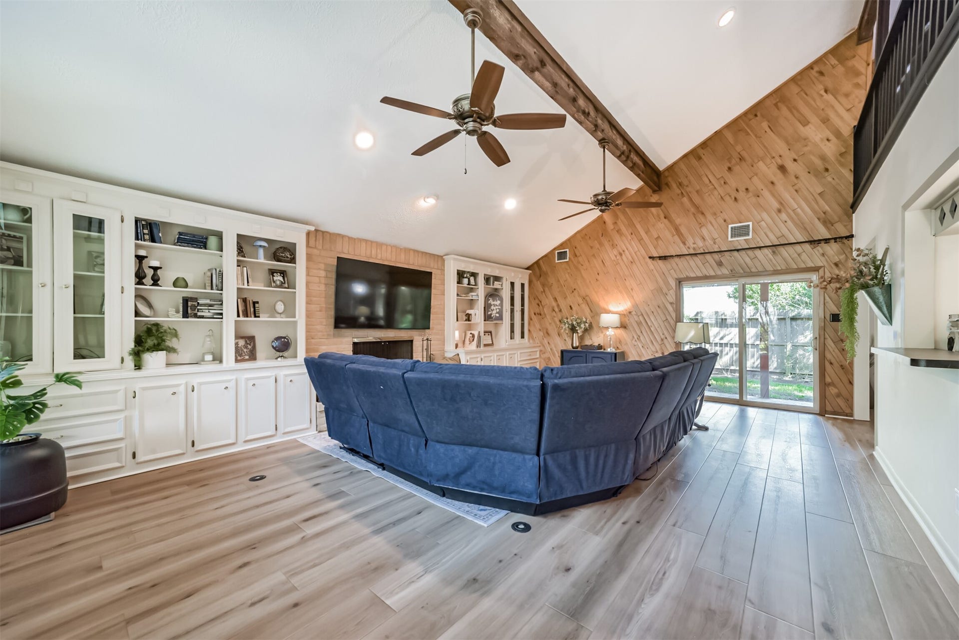 7618 Hurst Forest Drive, Humble, TX 77346 Soaring ceilings, exposed beams, and warm wood accents give this spacious living room personality. Extensive built-ins provide room for books, display pieces, and storage, while backyard access makes indoor and outdoor entertaining easy.