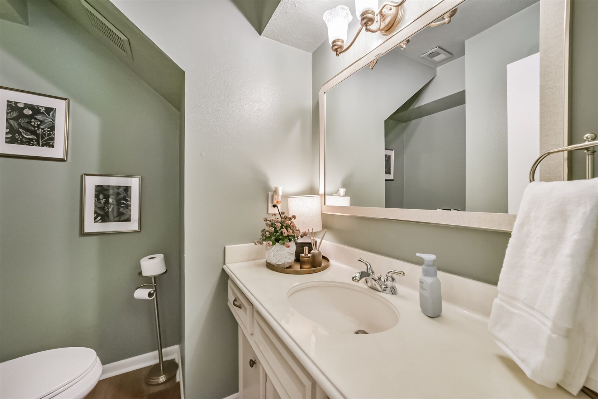 7618 Hurst Forest Drive, Humble, TX 77346 A charming powder room offers guests a convenient space to freshen up. Soft green walls, a framed mirror, and vanity storage bring warmth and function to this thoughtfully styled room.