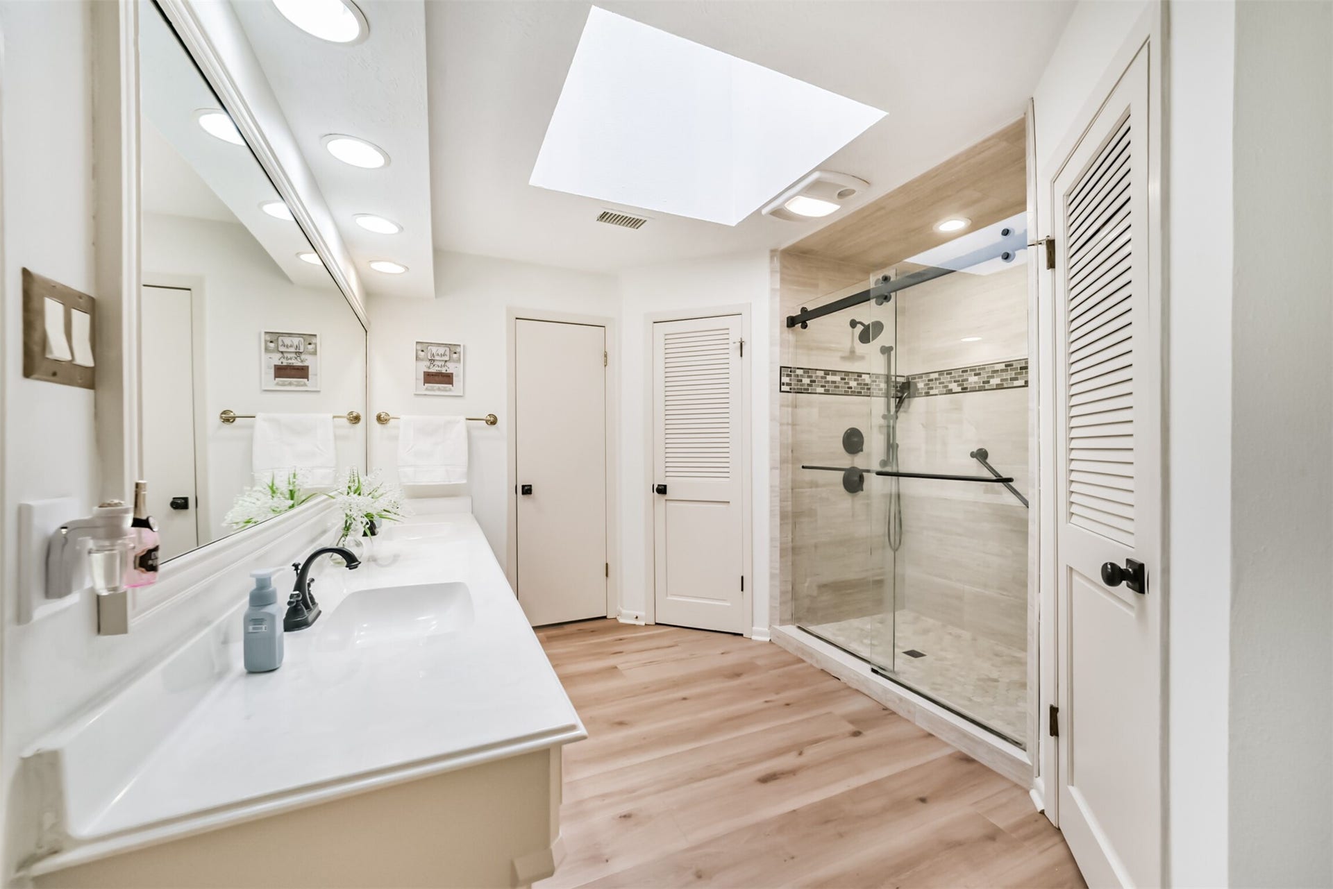 7618 Hurst Forest Drive, Humble, TX 77346 A skylight brightens this spacious bathroom, where a long vanity and glass-enclosed shower combine comfort with everyday function. Light finishes give the space an airy, refreshing feel.