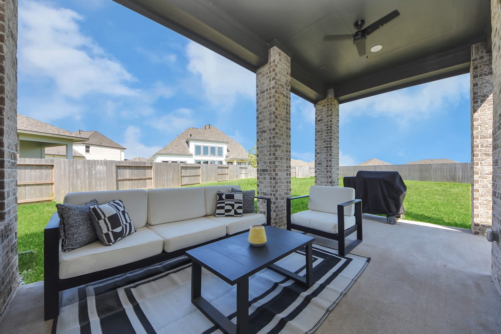 2995 Tantara Drive, Katy, TX 77493 Spacious covered patio with comfortable seating, ceiling fan, and a barbecue grill, perfect for outdoor entertaining with a view of the fenced backyard.