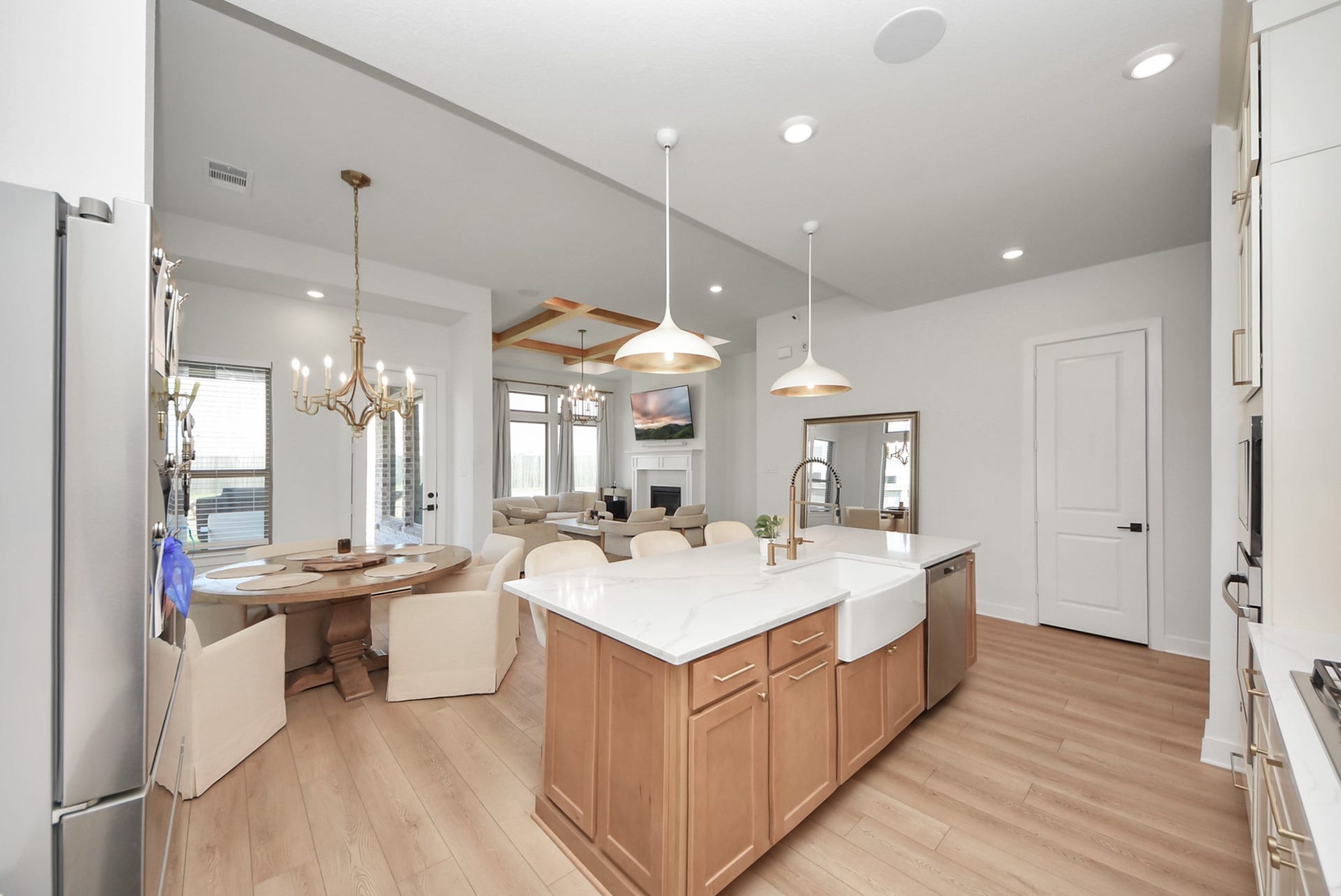 2995 Tantara Drive, Katy, TX 77493 Bright, open-concept kitchen and dining area featuring a large island with farmhouse sink, elegant pendant lighting, and a cozy living space with a fireplace.