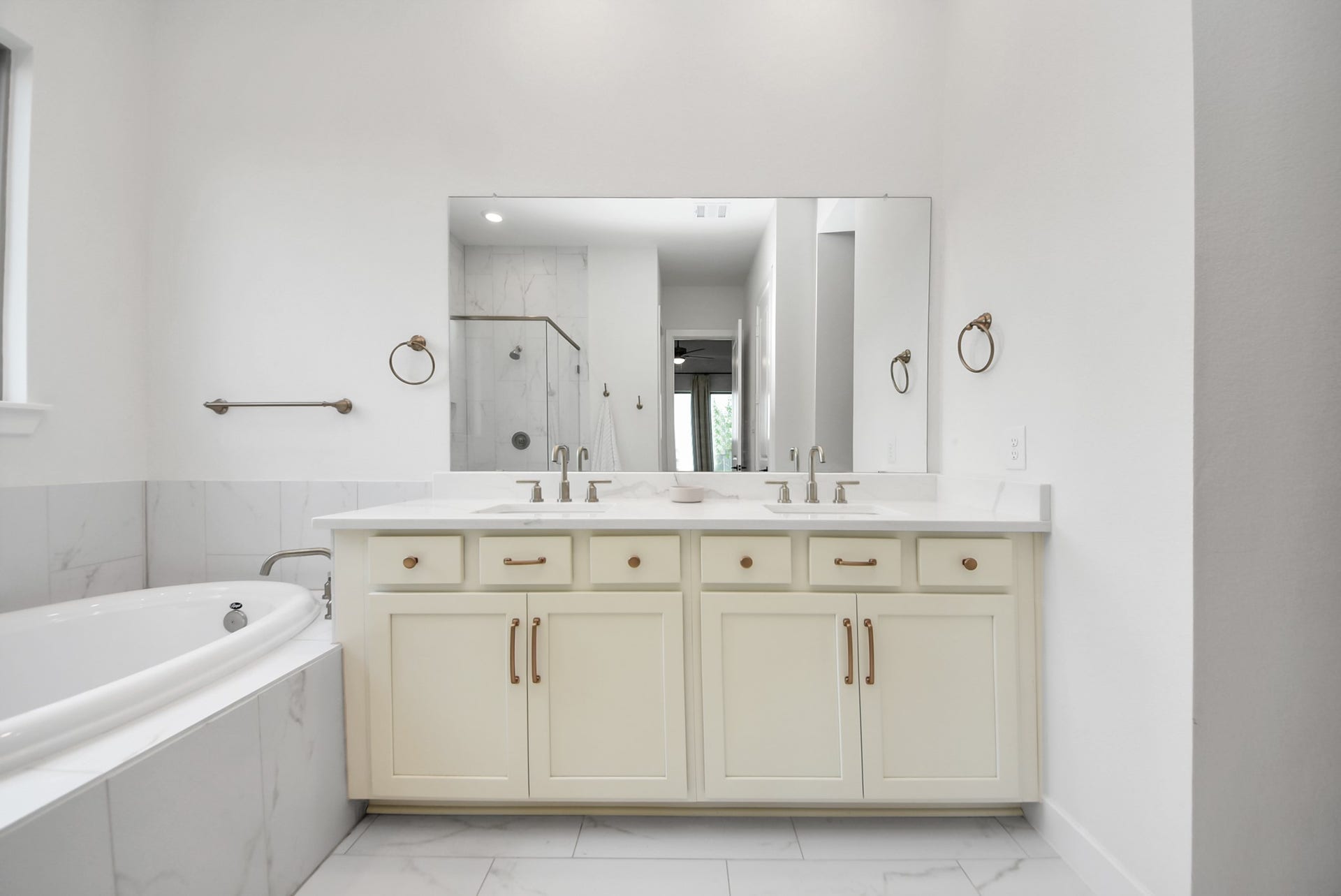 2995 Tantara Drive, Katy, TX 77493 Elegant bathroom featuring a spacious double vanity with sleek fixtures, a luxurious soaking tub, and a glass-enclosed shower, all accented by sophisticated tilework.