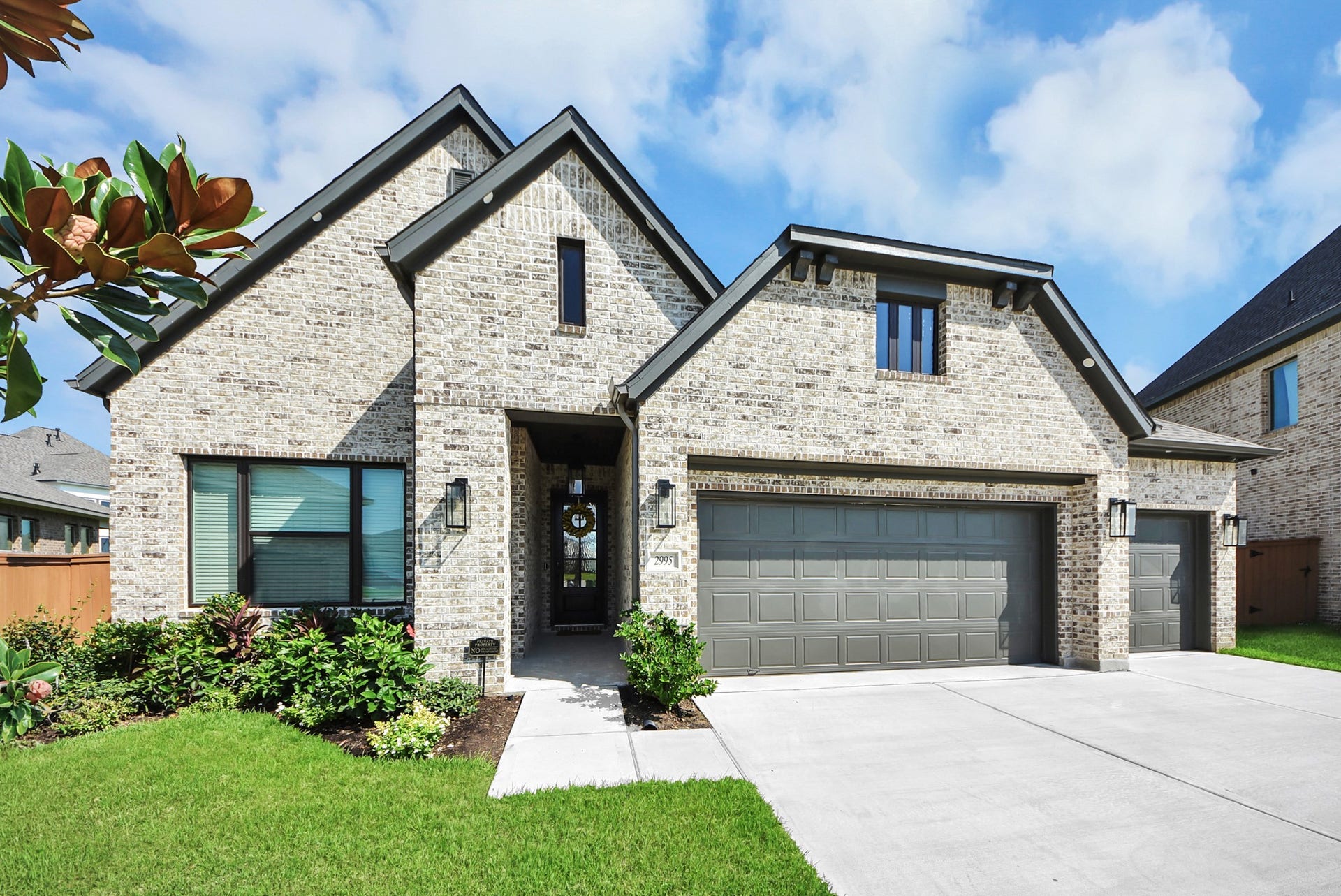 2995 Tantara Drive, Katy, TX 77493 Stunning brick home with a modern design features a spacious three-car garage, lush landscaping, and a welcoming entryway.