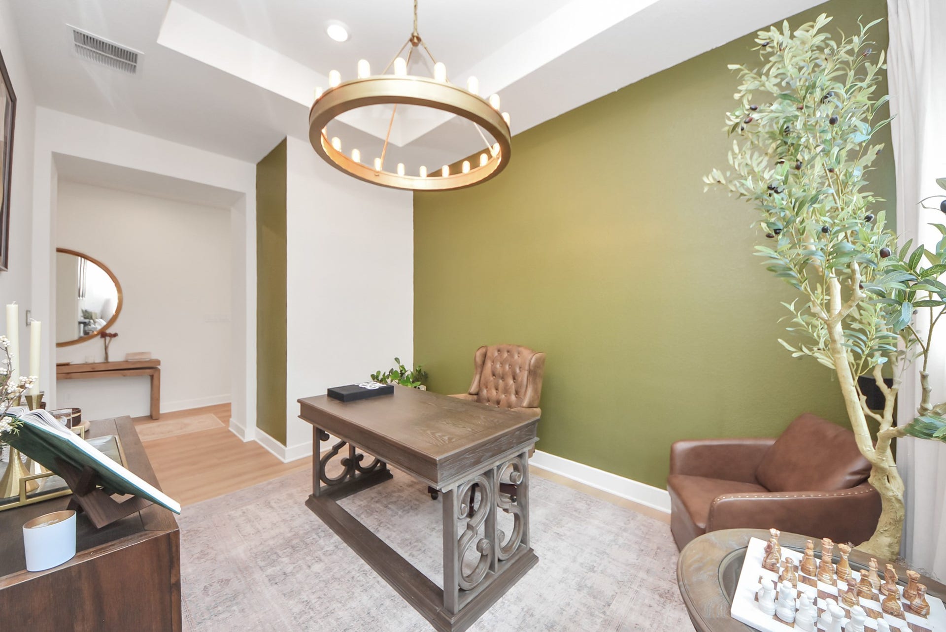 2995 Tantara Drive, Katy, TX 77493 Elegant home office featuring a striking green accent wall, stylish chandelier, and classic wood furniture, perfect for productivity and inspiration.
