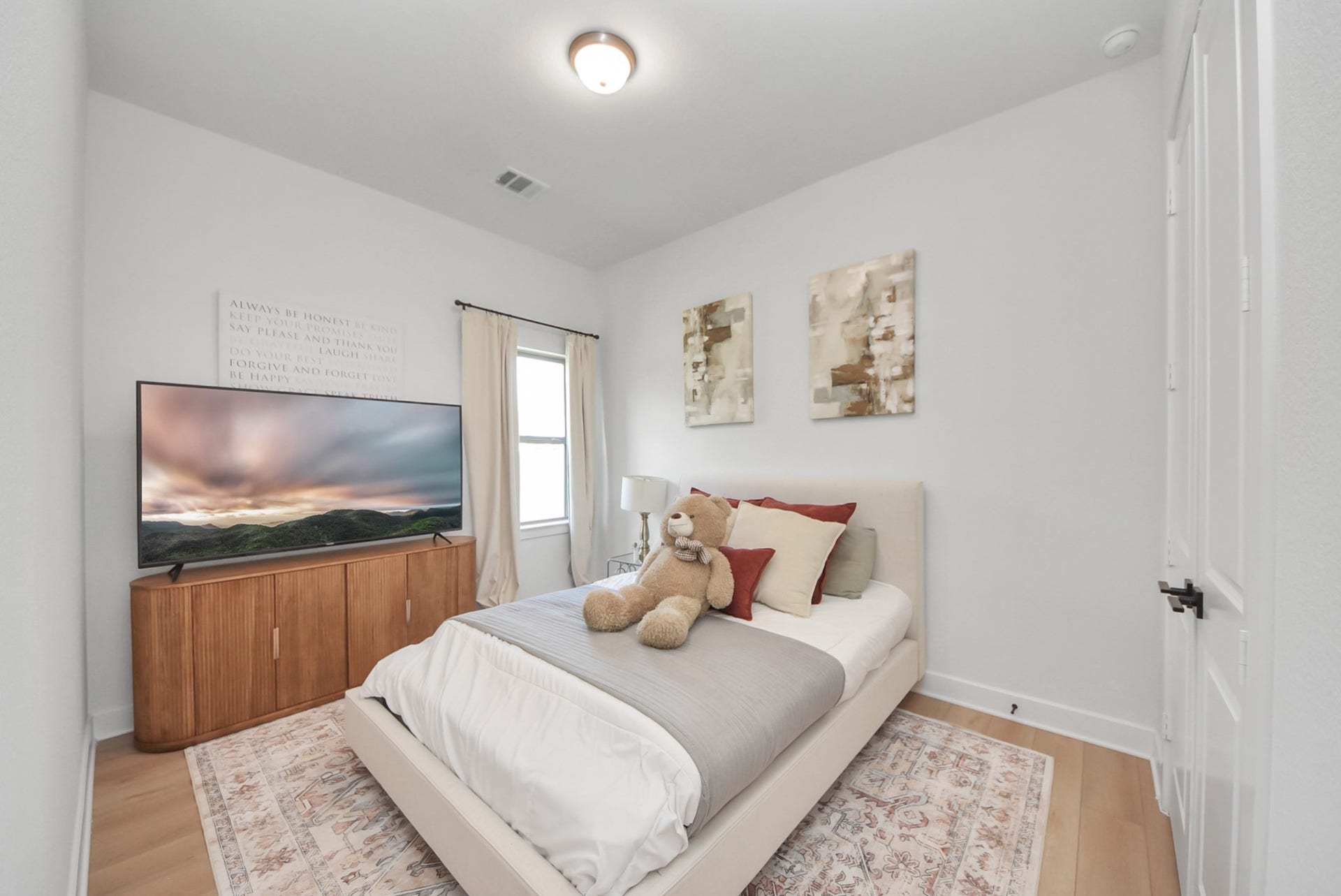 2995 Tantara Drive, Katy, TX 77493 Cozy bedroom with soft lighting, featuring a stylish bed, modern decor, and a large TV on a sleek wooden stand.