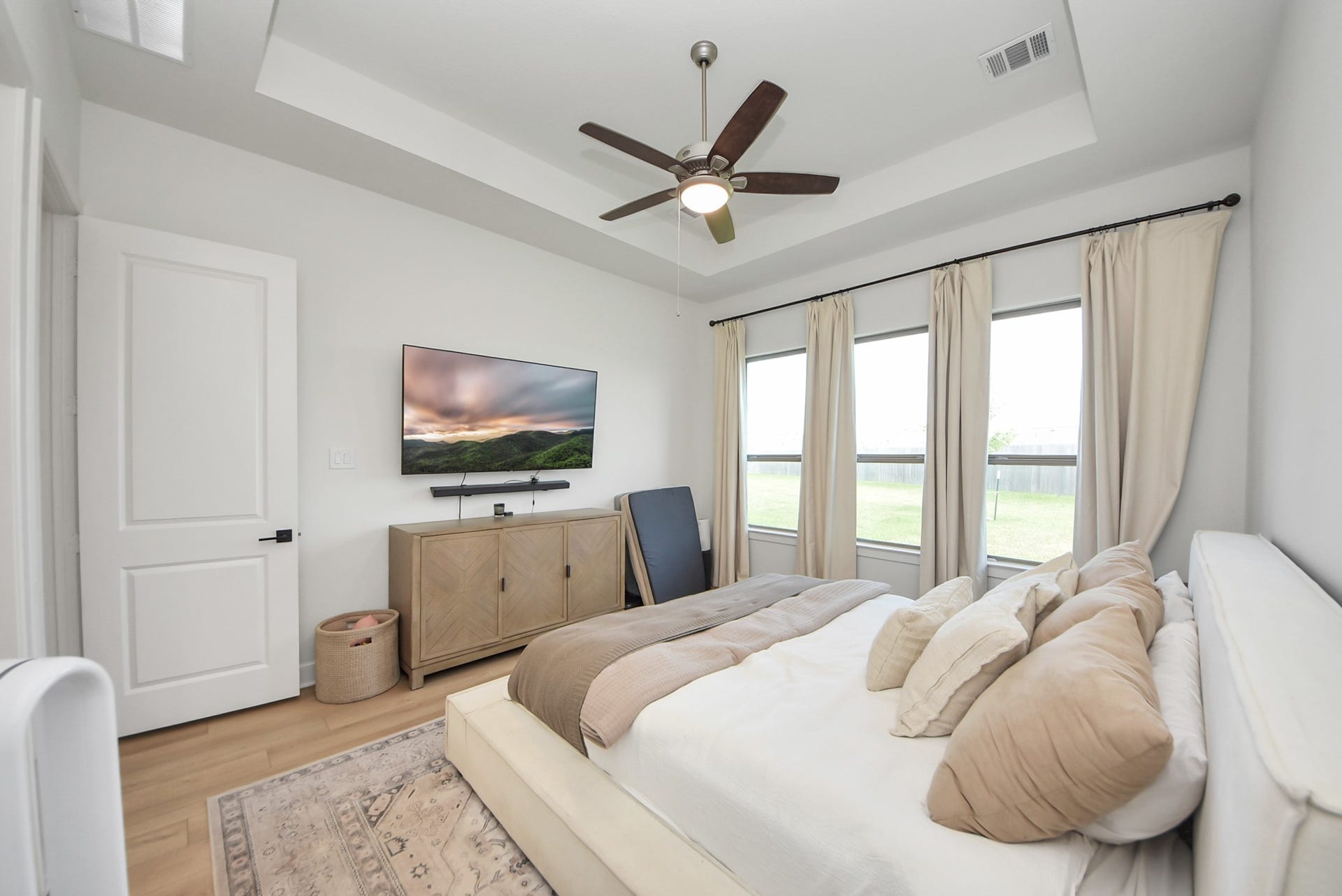2995 Tantara Drive, Katy, TX 77493 Bright and inviting bedroom featuring a tray ceiling, stylish ceiling fan, large windows with elegant drapes, and a cozy bed for ultimate relaxation.