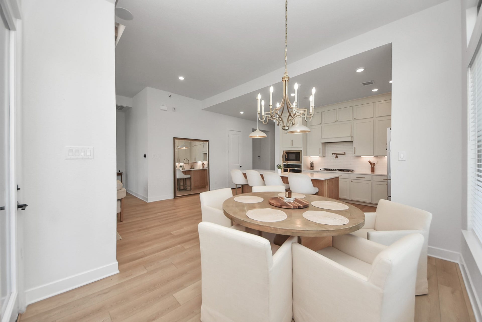 2995 Tantara Drive, Katy, TX 77493 Elegant open-concept dining area with a stylish chandelier, adjacent to a modern kitchen featuring sleek cabinetry and stainless-steel appliances.