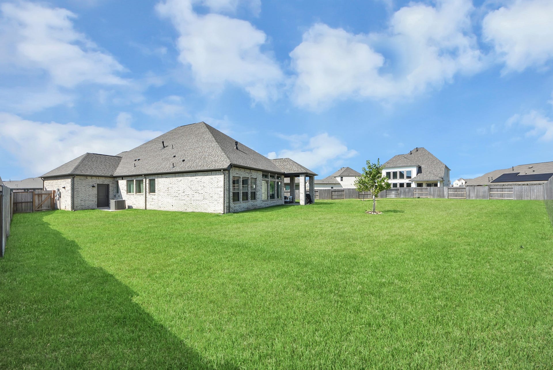 2995 Tantara Drive, Katy, TX 77493 Expansive backyard with lush green lawn and a charming brick exterior, perfect for outdoor activities and entertaining.