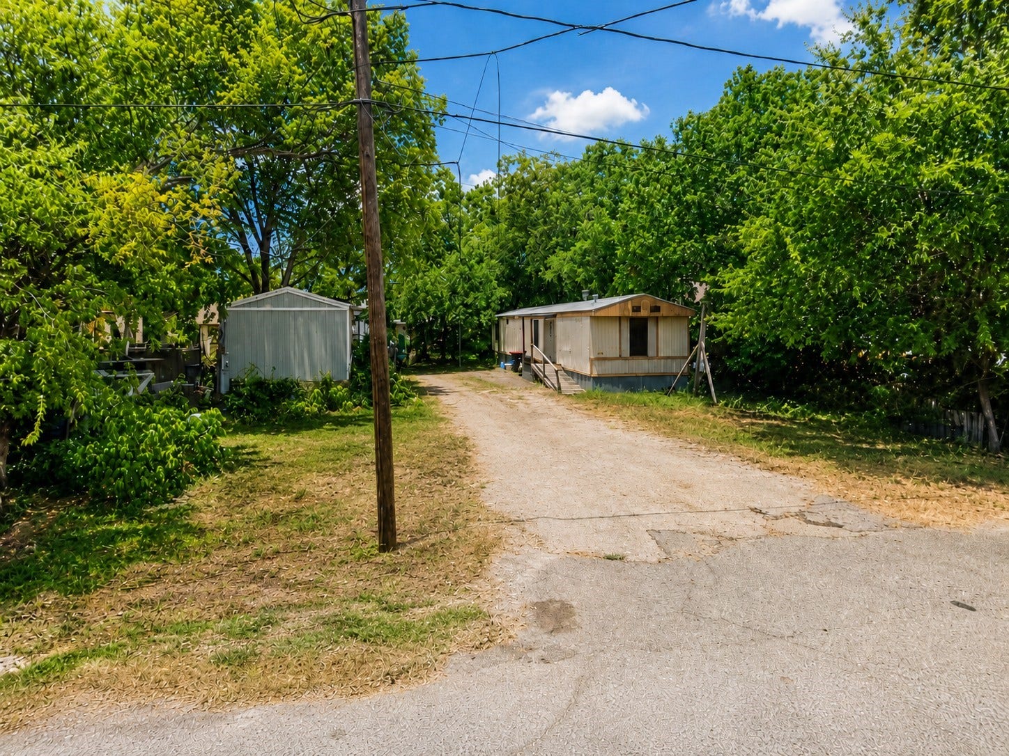 Spacious front entry with an extended driveway and a generous lot offering ample parking and outdoor space, creating a private setting with convenient street access. Property includes two mobile homes currently used as rental units with tenants in place, offering income-producing potential.