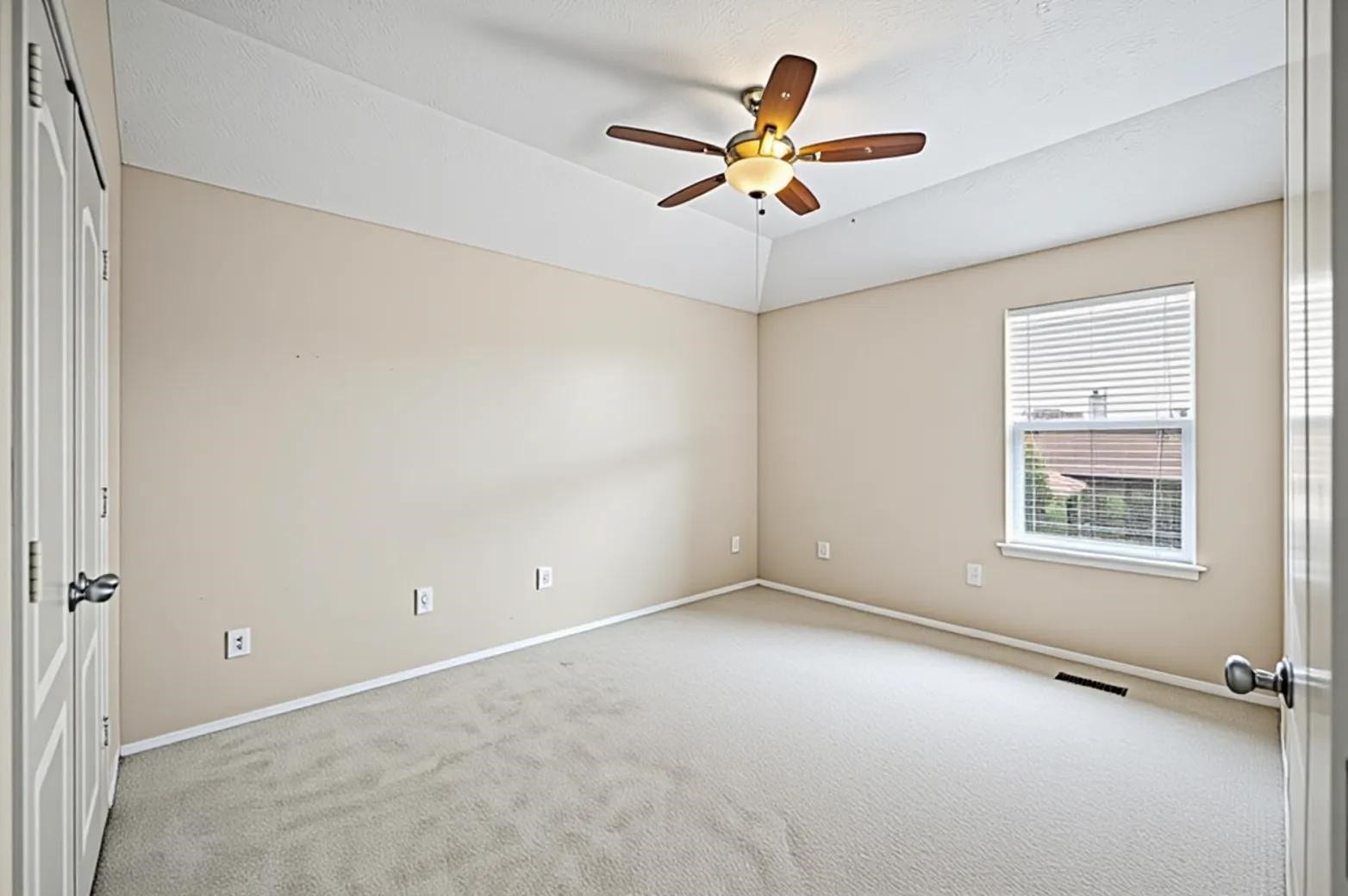8711 Sandusky Court, Tomball, TX 77375 This is a bright, empty 3rd bedroom featuring neutral walls, carpeted flooring, an elegant ceiling fan, and plenty of optional natural light. There's also a closet with double doors, making it a versatile space.