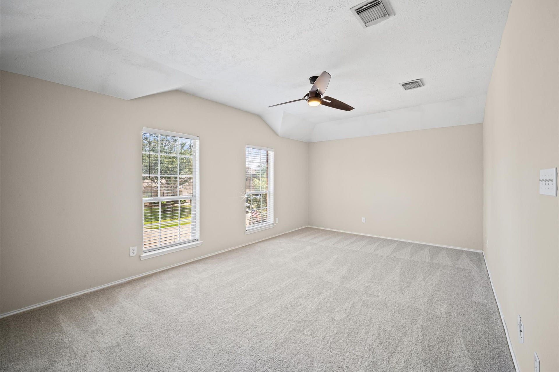 8711 Sandusky Court, Tomball, TX 77375 Spacious, bright room with neutral walls, large windows, and new carpet. Features a ceiling fan and ample natural light.