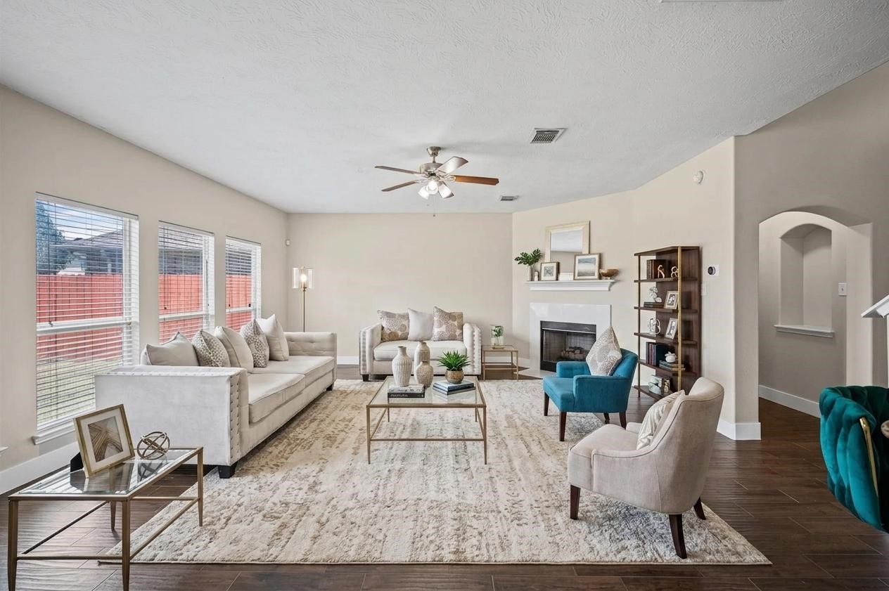 8711 Sandusky Court, Tomball, TX 77375 Spacious living room with abundant natural light from large windows, featuring elegant wood flooring, a cozy fireplace, and modern furnishings. Ideal for relaxation and entertaining.
