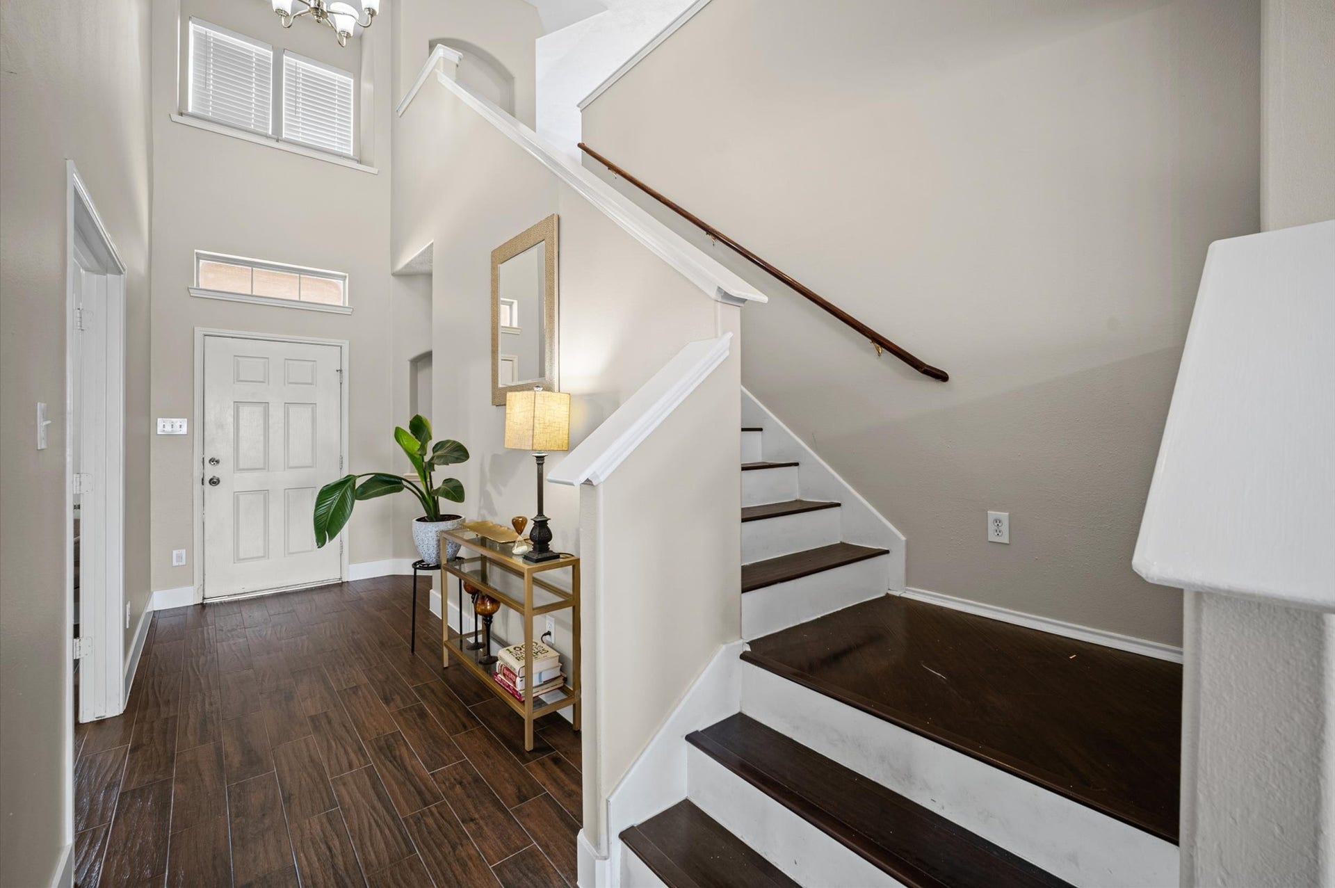 8711 Sandusky Court, Tomball, TX 77375 This inviting entryway features a high ceiling and natural light. It has a modern staircase with dark wood steps, a stylish console table, and a plant, creating a welcoming atmosphere.