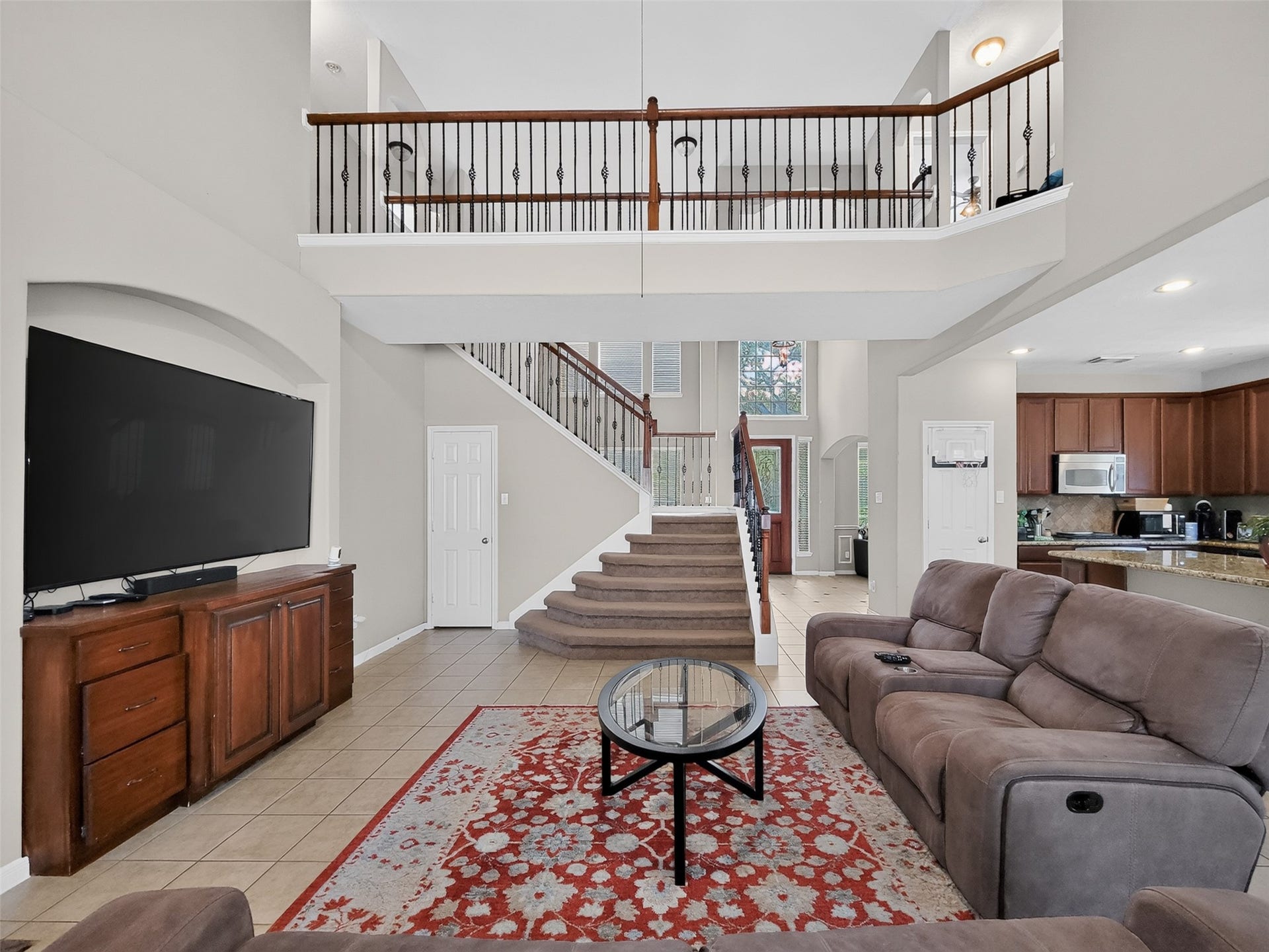 2006 Linden Cove Court, Katy, TX 77494 Spacious living room with high ceilings, a grand staircase, and an open view to the kitchen. Features a cozy seating area, large TV, and elegant railing on the upper level.