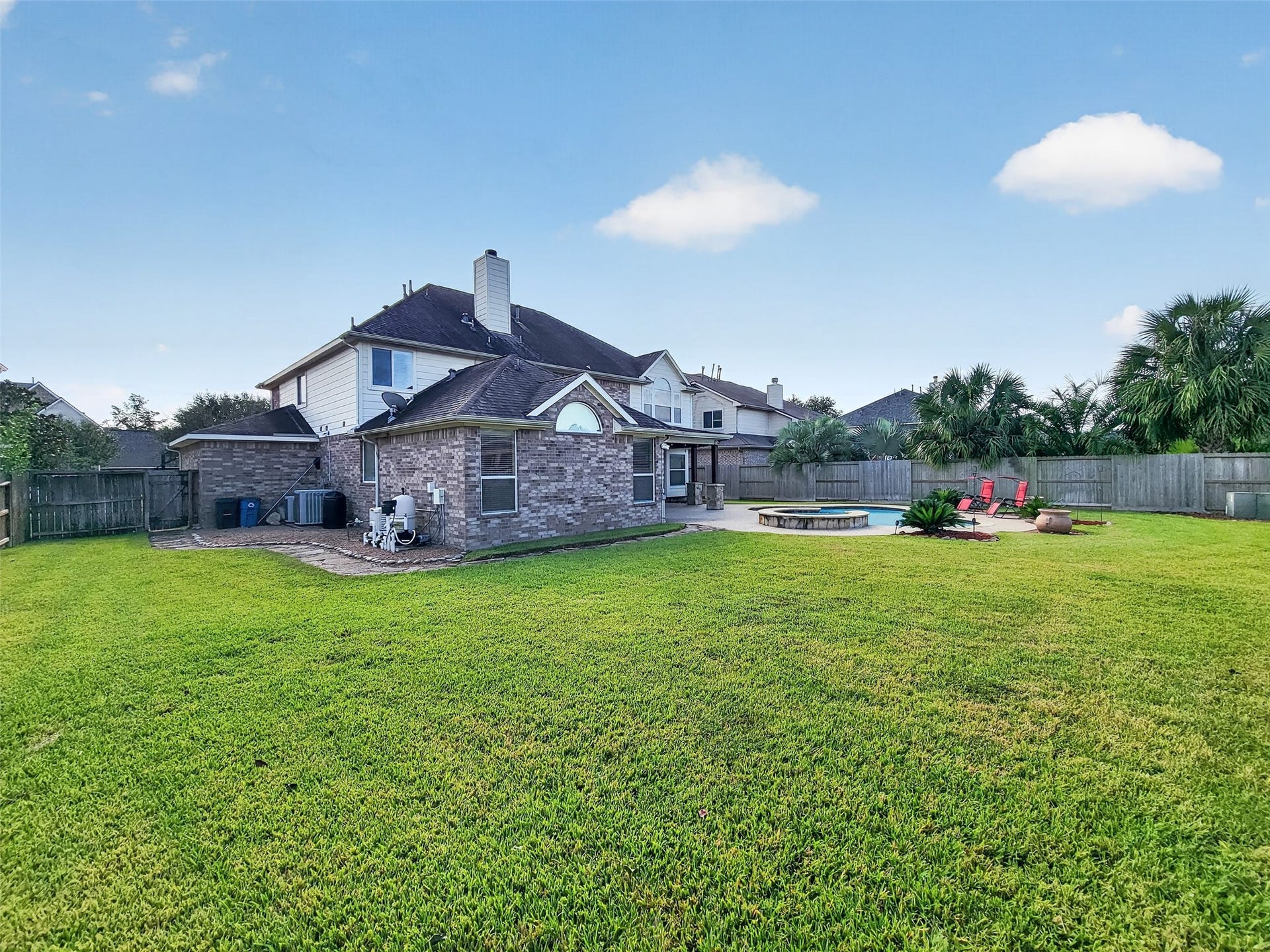 2006 Linden Cove Court, Katy, TX 77494 Expansive backyard with lush green lawn, featuring a brick exterior, patio area, and inviting pool for outdoor relaxation and entertainment.
