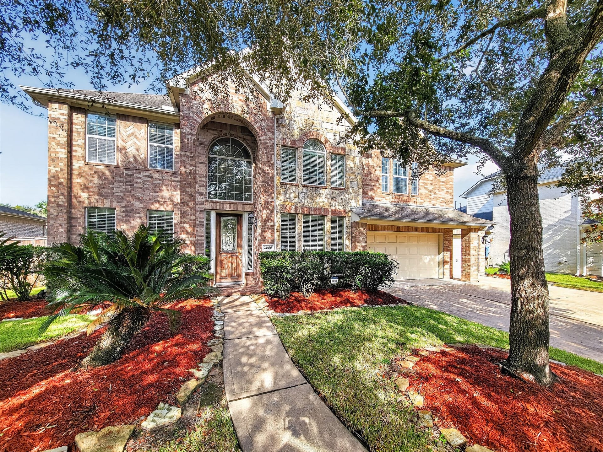 2006 Linden Cove Court, Katy, TX 77494 Stunning two-story brick home with elegant arched windows, a welcoming pathway, and lush landscaping, offering great curb appeal and a spacious two-car garage.