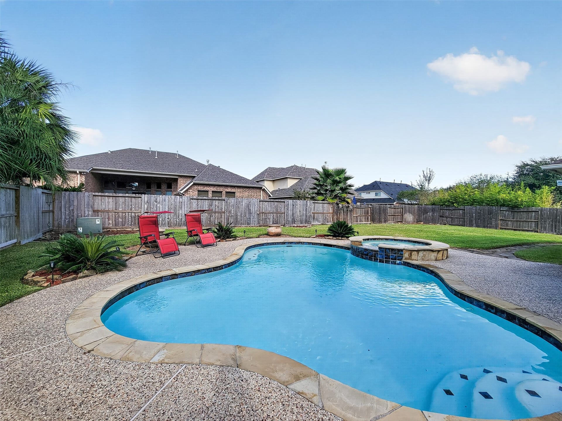 2006 Linden Cove Court, Katy, TX 77494 Charming backyard oasis featuring a sparkling pool with a spa, surrounded by a spacious patio and lush landscaping, perfect for relaxation and entertaining.