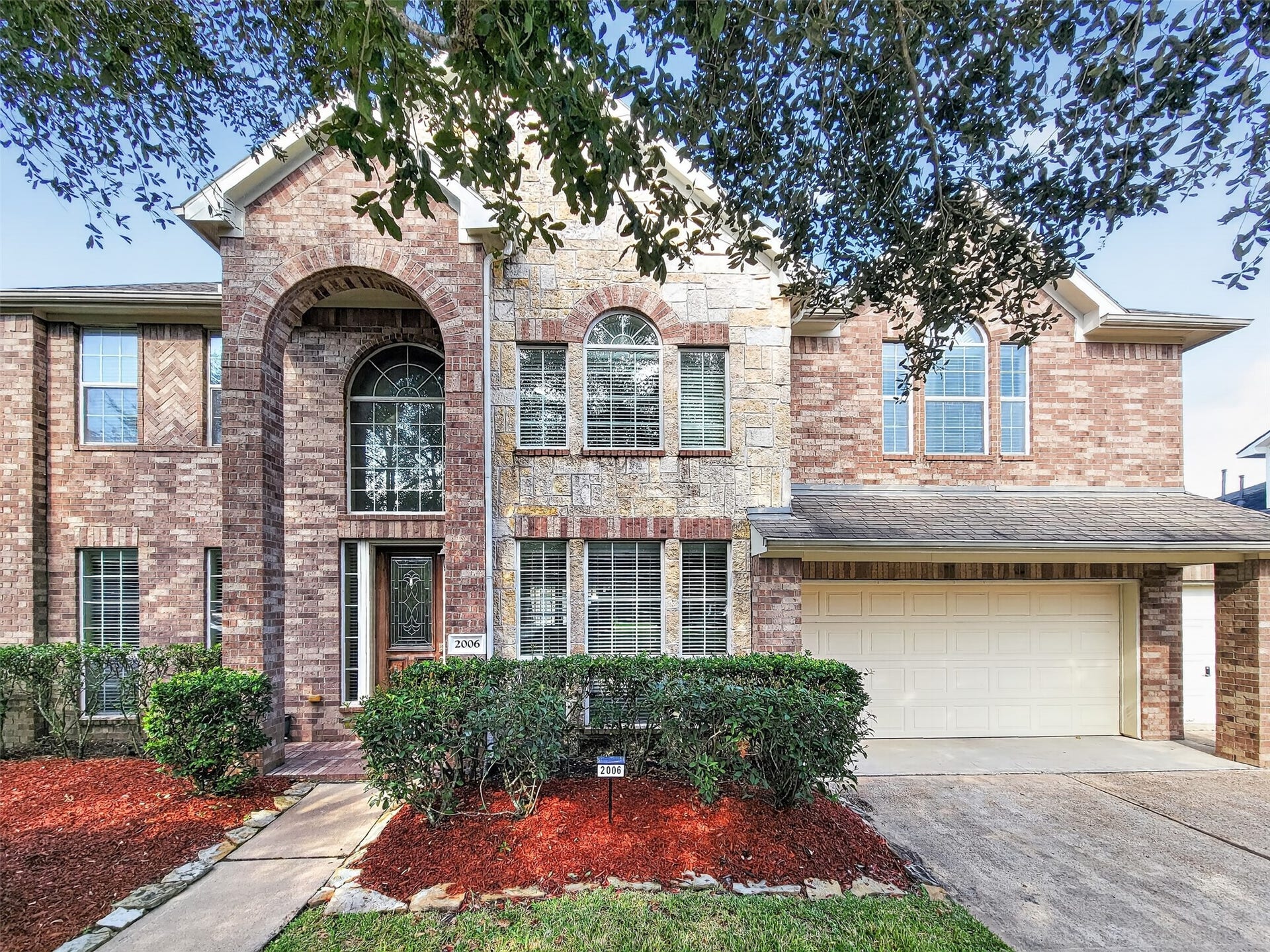 2006 Linden Cove Court, Katy, TX 77494 Stunning two-story brick home featuring elegant archways, large windows, and a welcoming entrance, complemented by a spacious two-car garage and well-maintained landscaping.