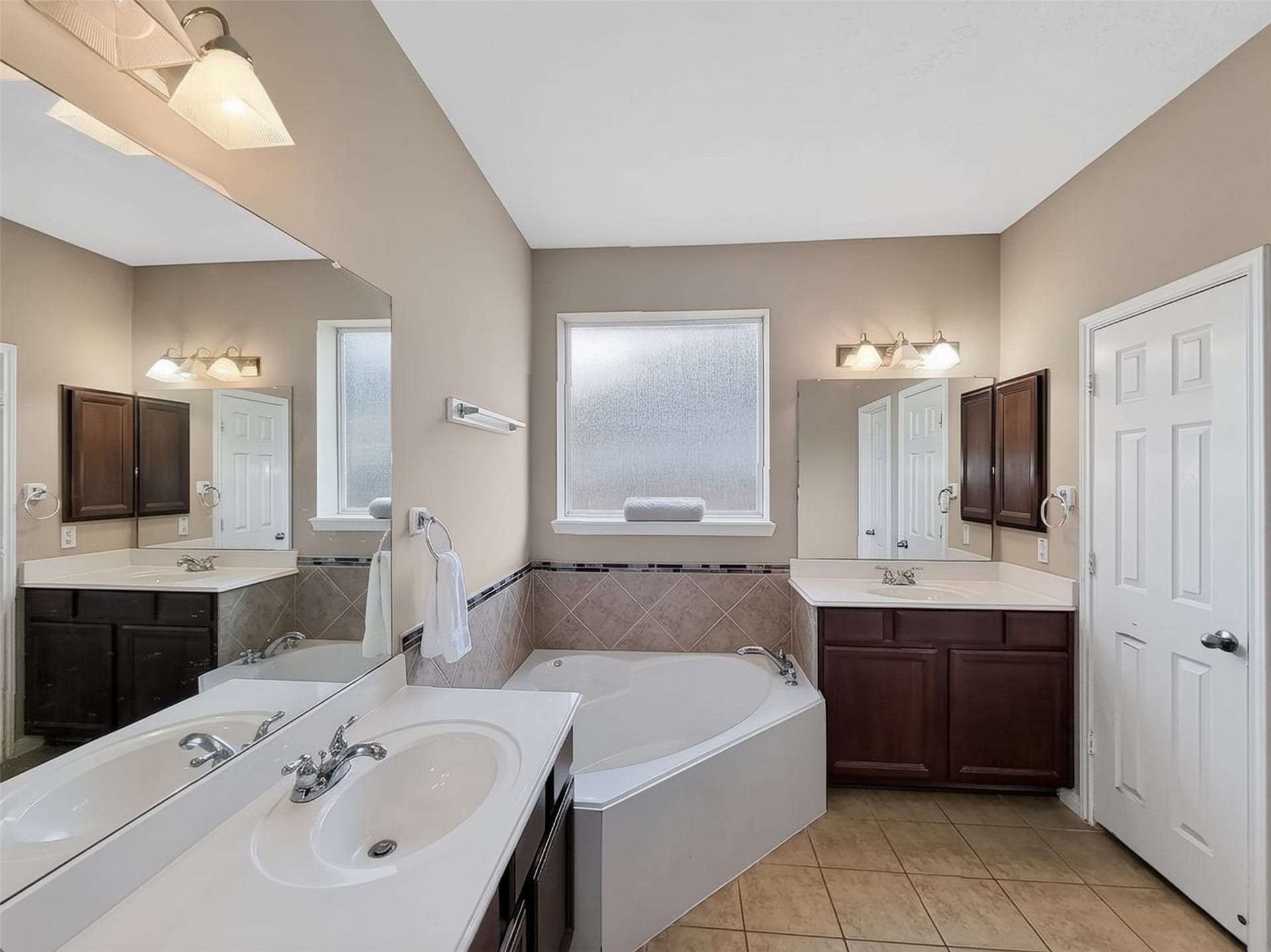 2006 Linden Cove Court, Katy, TX 77494 Elegant bathroom featuring a spacious corner soaking tub, dual sinks with ample counter space, and rich dark wood cabinetry, complemented by soft lighting and tiled flooring.