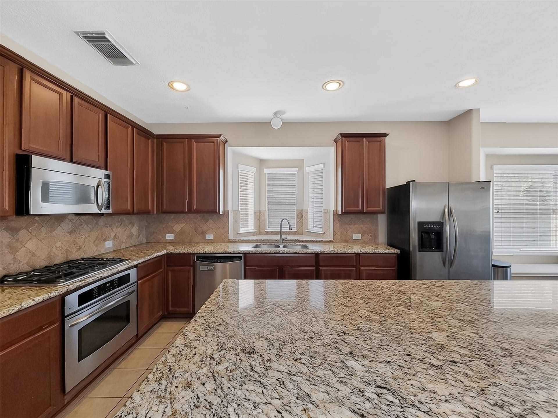 2006 Linden Cove Court, Katy, TX 77494 Spacious kitchen featuring elegant granite countertops, stainless steel appliances, and rich wood cabinetry, perfect for culinary enthusiasts.
