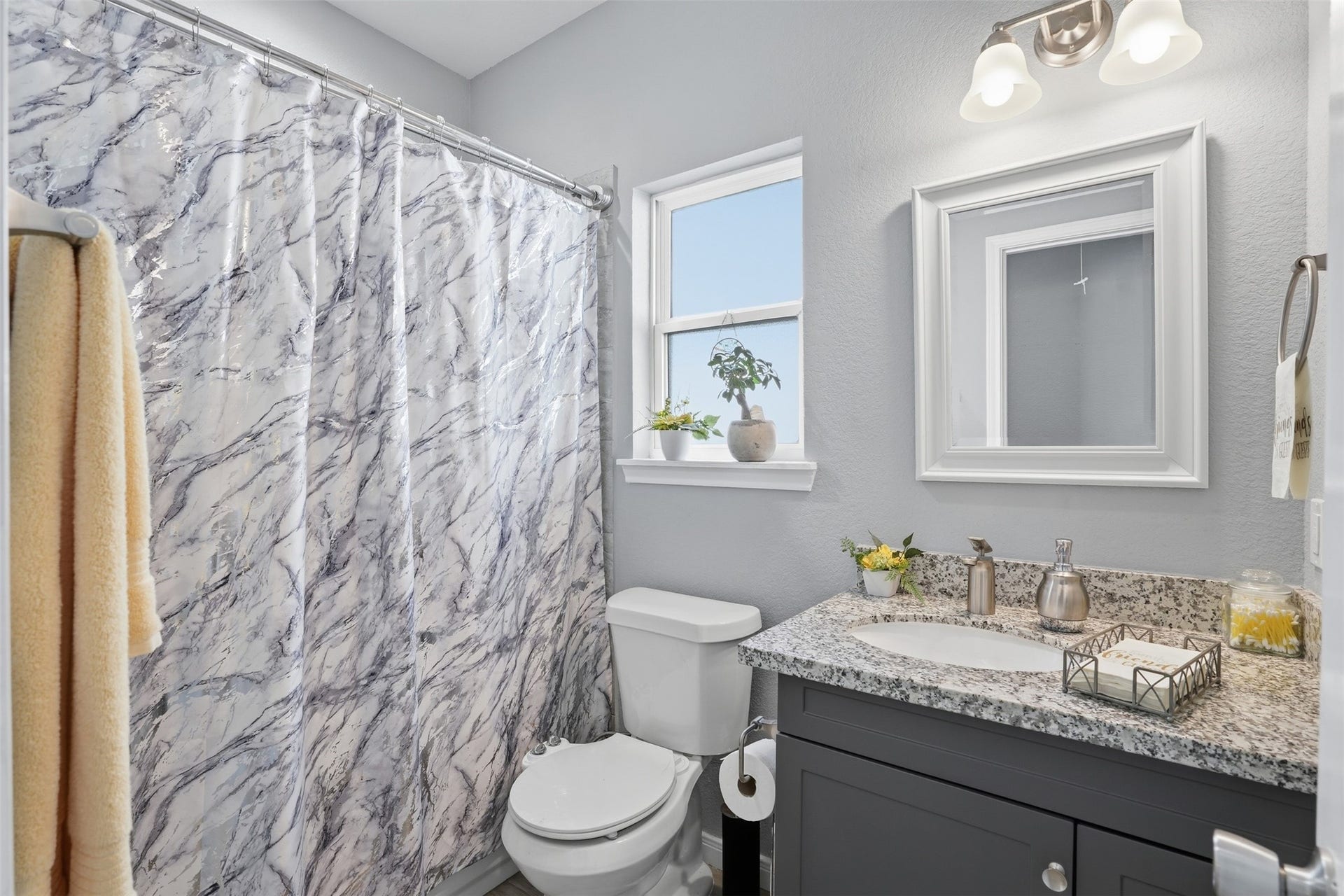 16740 Stonefield, Montgomery, TX 77316 Bright and inviting bathroom featuring a marbled shower curtain, sleek granite countertop, and modern fixtures for a fresh, contemporary feel.