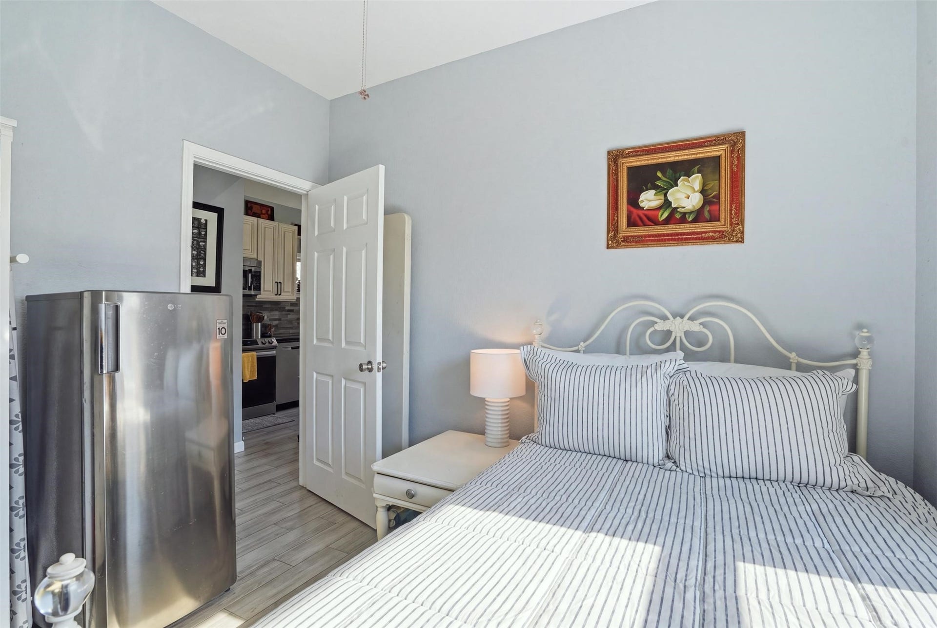 16740 Stonefield, Montgomery, TX 77316 Bedroom with soft gray walls, featuring a stylish metal bed frame and striped bedding, complemented by a bedside lamp and decorative artwork.