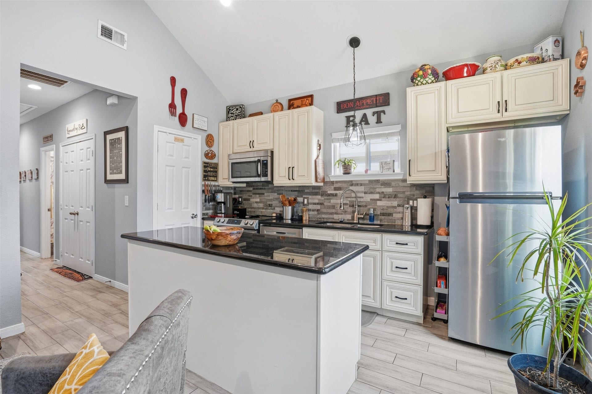 16740 Stonefield, Montgomery, TX 77316 Kitchen with modern stainless steel appliances, elegant cabinetry, and a stylish tile backsplash. The breakfast bar and abundant natural light create a welcoming atmosphere.