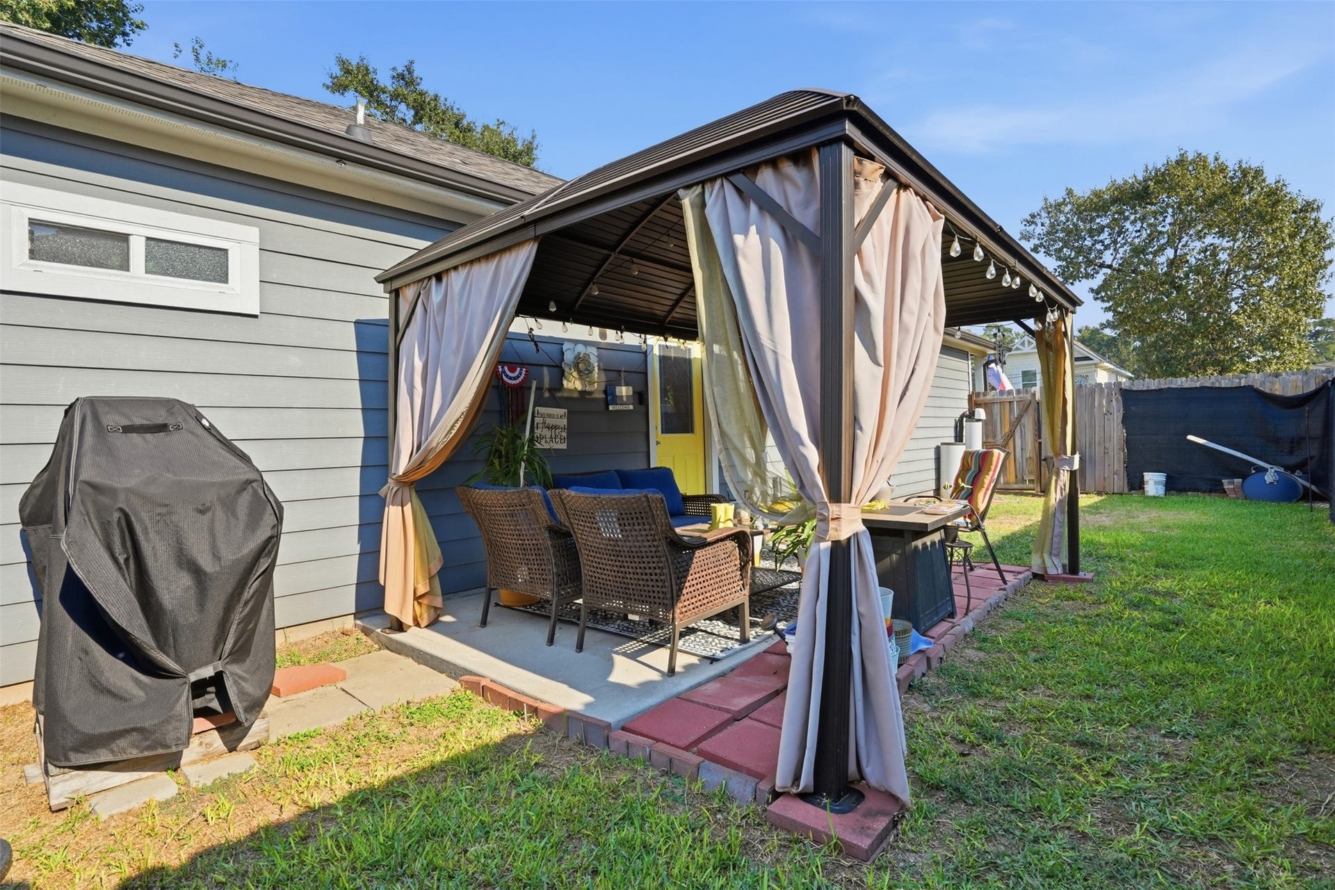 16740 Stonefield, Montgomery, TX 77316 Backyard retreat featuring a cozy gazebo with curtains, perfect for outdoor relaxation and entertaining.