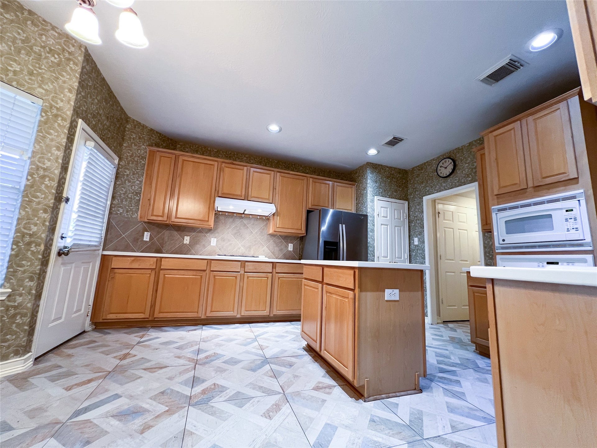 908 Azalea Pointe, League City, TX 77573 Spacious and inviting, this kitchen boasts warm wooden cabinetry, sleek appliances, and a stylish tile floor, perfect for both cooking and entertaining.