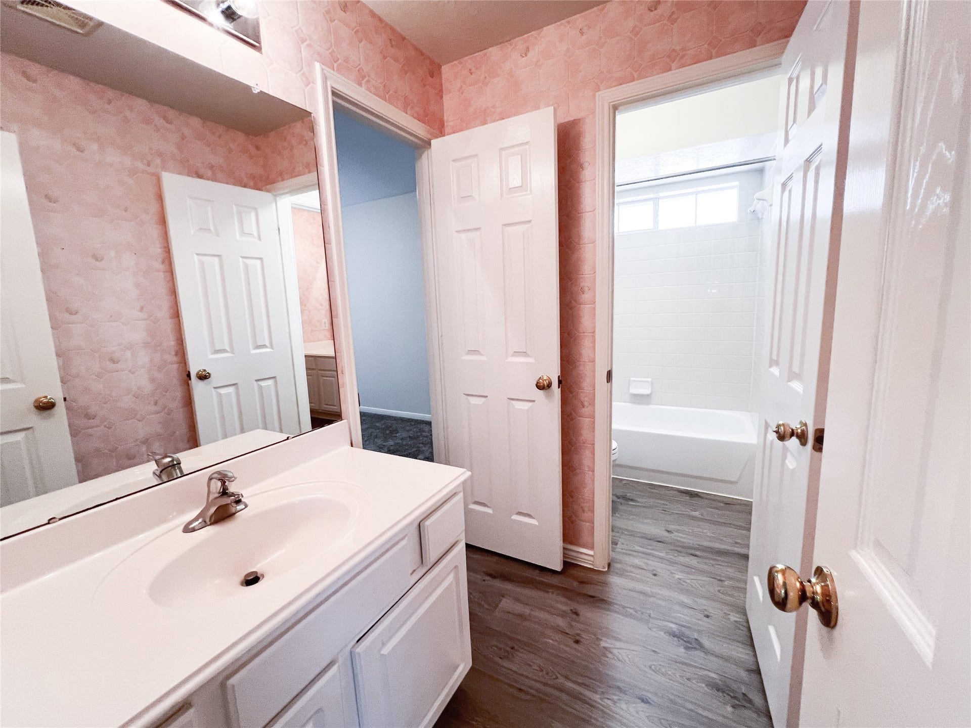 908 Azalea Pointe, League City, TX 77573 Discover the charm of this inviting second-floor bathroom, featuring elegant pink wallpaper, a pristine white vanity, and a full bathtub for ultimate relaxation.