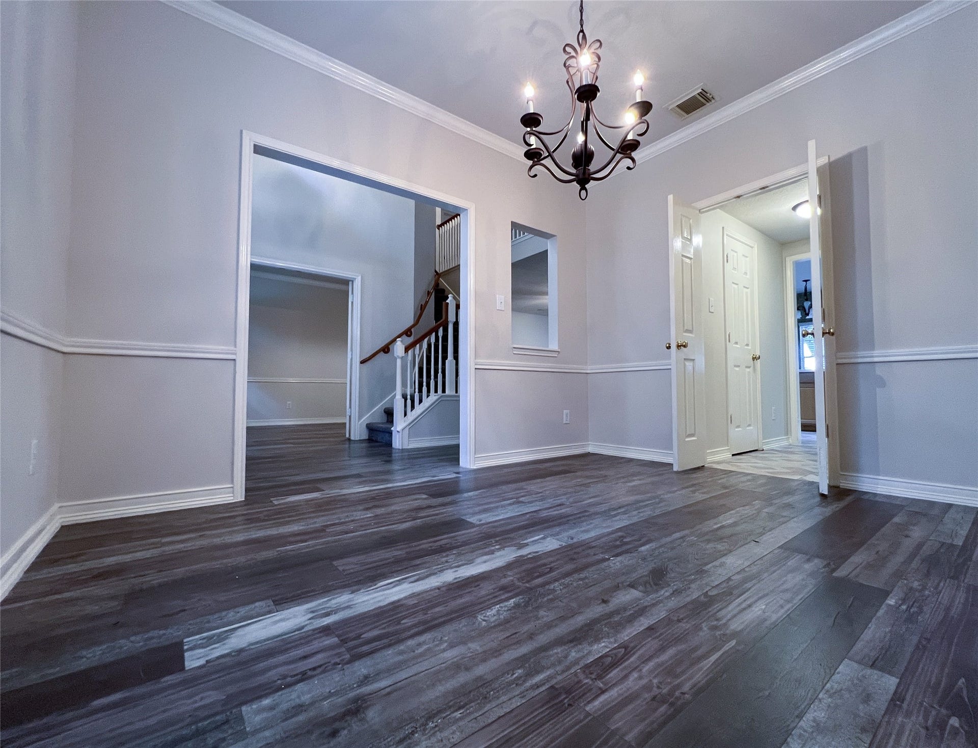 908 Azalea Pointe, League City, TX 77573 Elegantly designed dining room featuring rich flooring, classic wainscoting, and a stunning chandelier, creating the perfect ambiance for memorable gatherings.