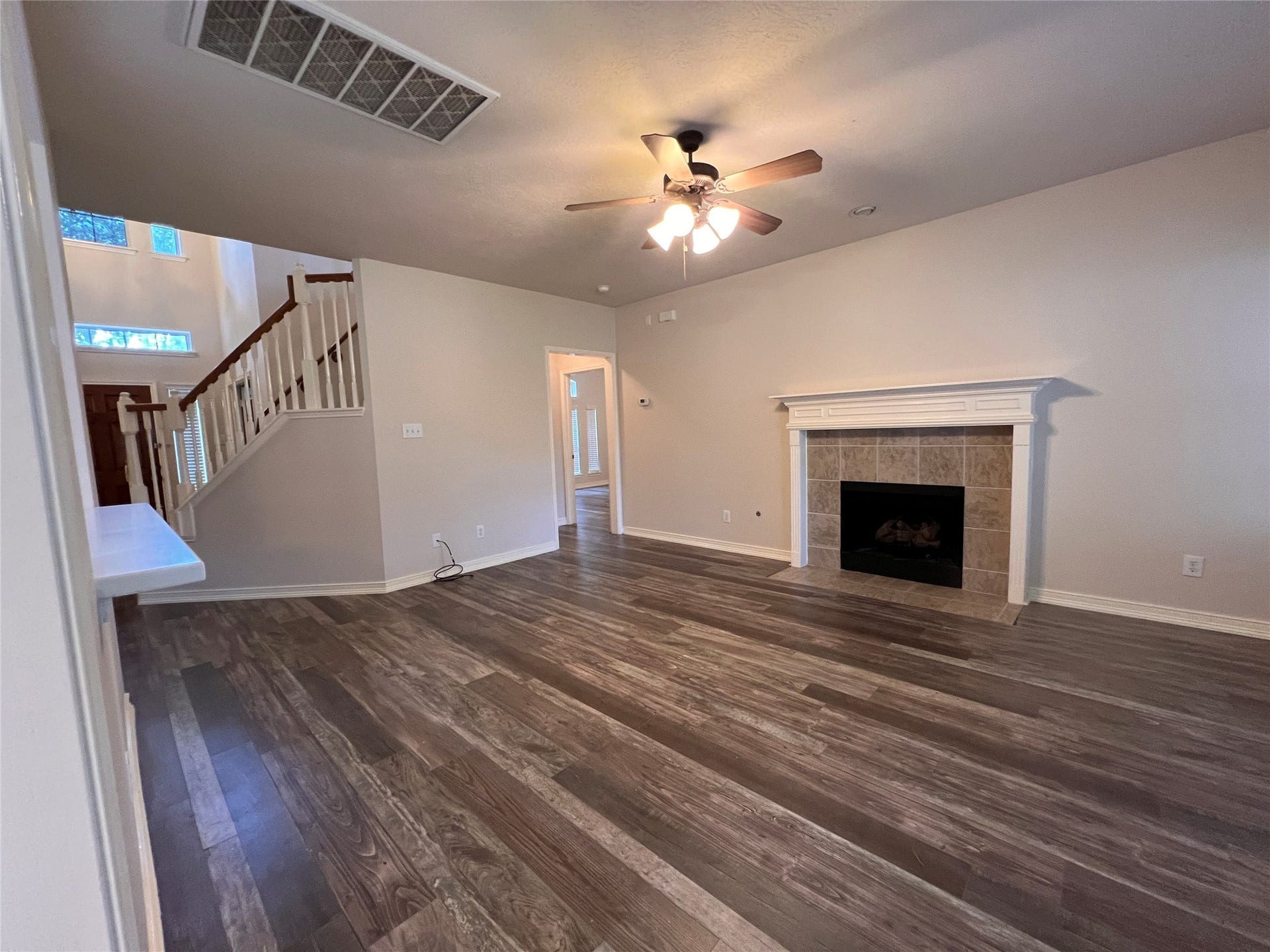 908 Azalea Pointe, League City, TX 77573 Experience the warmth and elegance of this inviting living area, featuring rich flooring, a cozy fireplace, and a stylish ceiling fan, all beautifully illuminated by natural light from the open staircase and adjacent spaces.