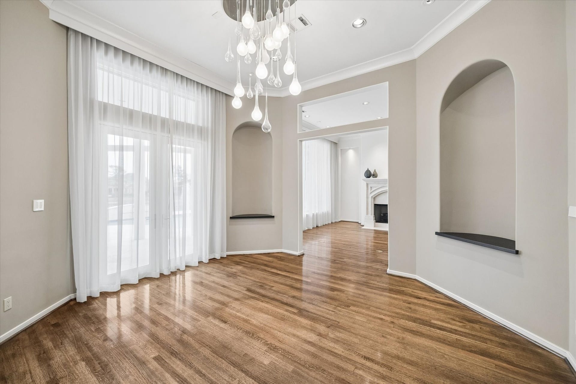 FORMAL DINING ROOM WITH ACCESS TO THE COVERED TERRACE - contemporary chandelier and recessed accent lighting, handsome hardwood flooring, sheer draperies for filtered lighting, dual arched niches for display - easy flow between living and dining for entertaining