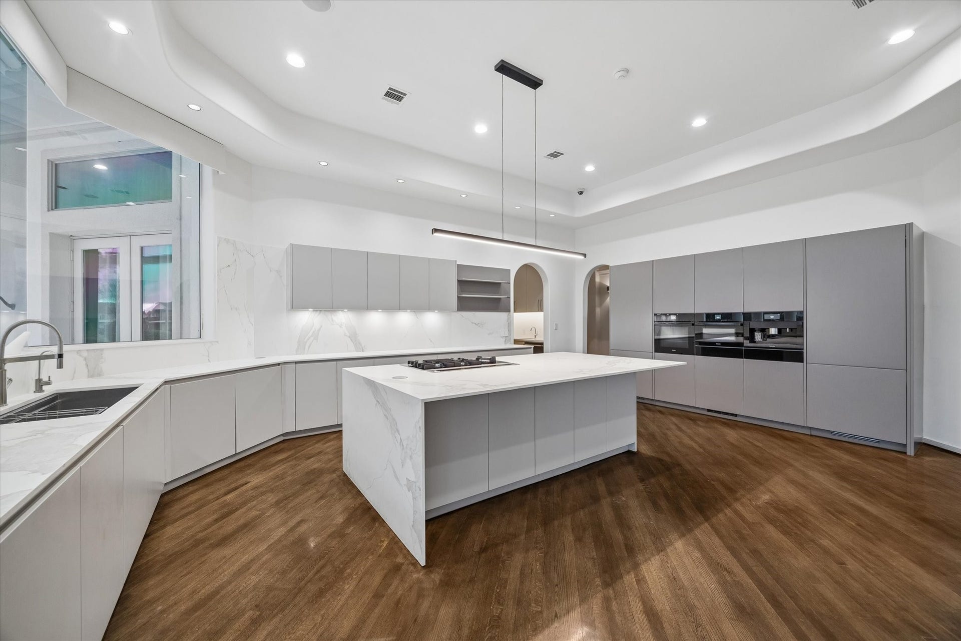 STUNNING ITALIAN 'CANTONI' CUSTOM DESIGN KITCHEN CABINETRY FITTED WITH MIELE AND GAGGENAU APPLIANCES - dual Gaggenau refrigerator/freezers, Miele ovens and coffee system - recessed lighting, under-cabinet lighting and a dramatic 'light bar' over the large island - beautiful 'Porcelaine' countertops with 'waterfall' edge on the oversize island, and convenient island seating for barstools - + beautiful views from the butt-glass window