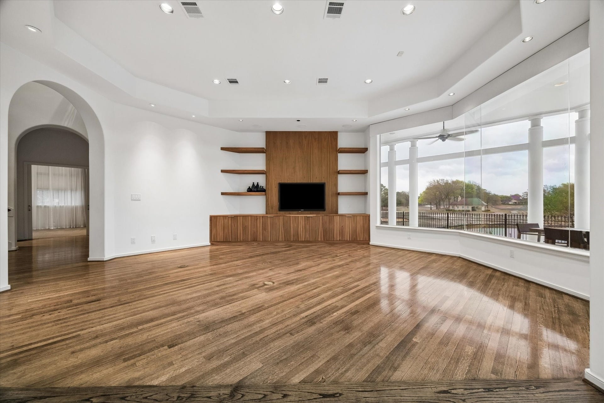 SPACIOUS FAMILY ROOM DESIGNED FOR COMFORTABLE LIVING AND ENTERTAINING - contemporary built-in cabinetry and open shelving with multiple cabinets for entertainment equipment and storage, recessed lighting - sleek design of the wide butt-glass window, with stunning views overlooking the covered terrace out to the lake and golf course