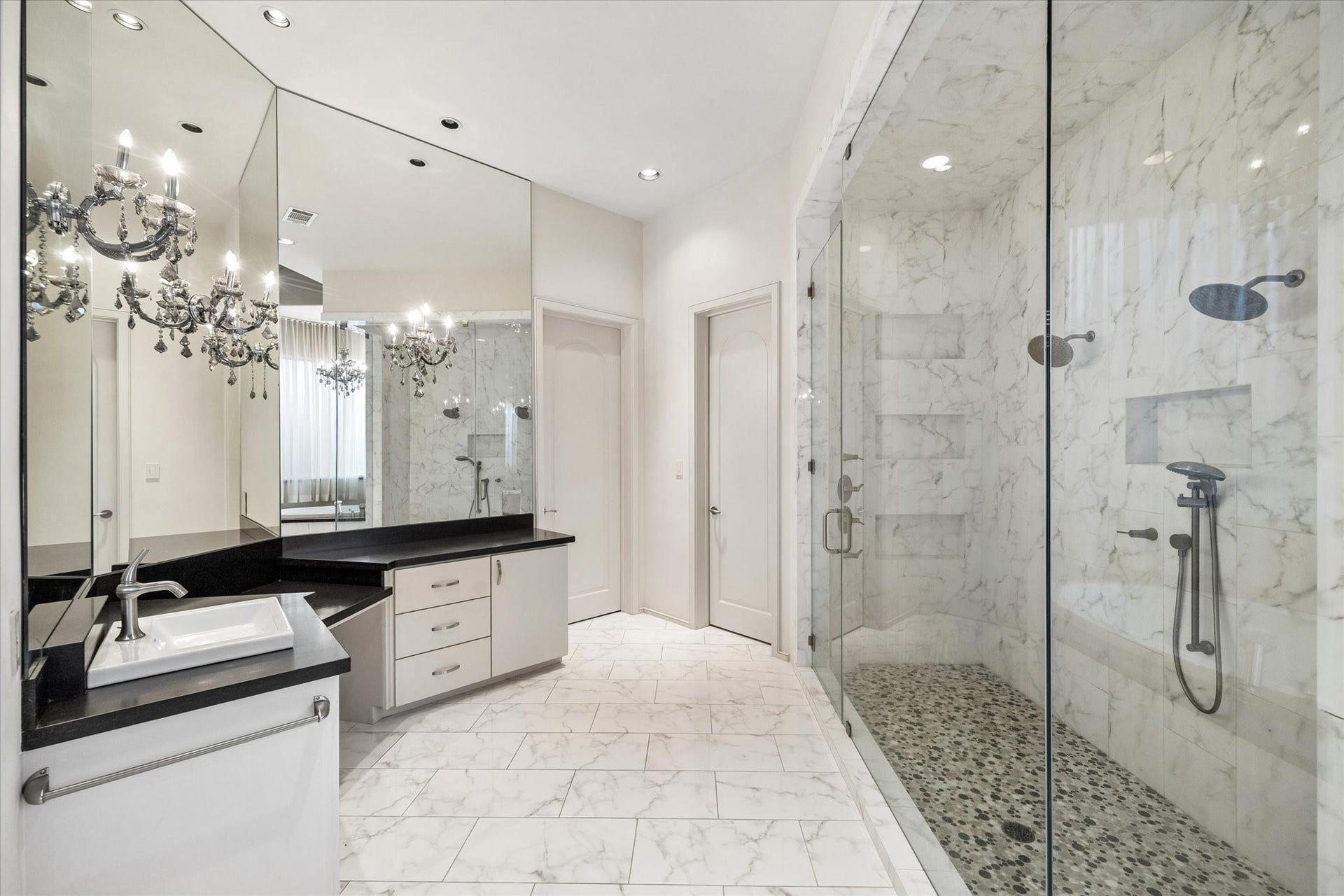 ANOTHER VIEW OF THE SPA-LIKE PRIMARY BATH RETREAT - a 2nd vanity area with built-in 'dressing table' space, large mirrors accented with sconces, door to right of vanity leads into the 2nd walk-in closet fitted with glazed-insert doors protecting clothing with hanging space and storage