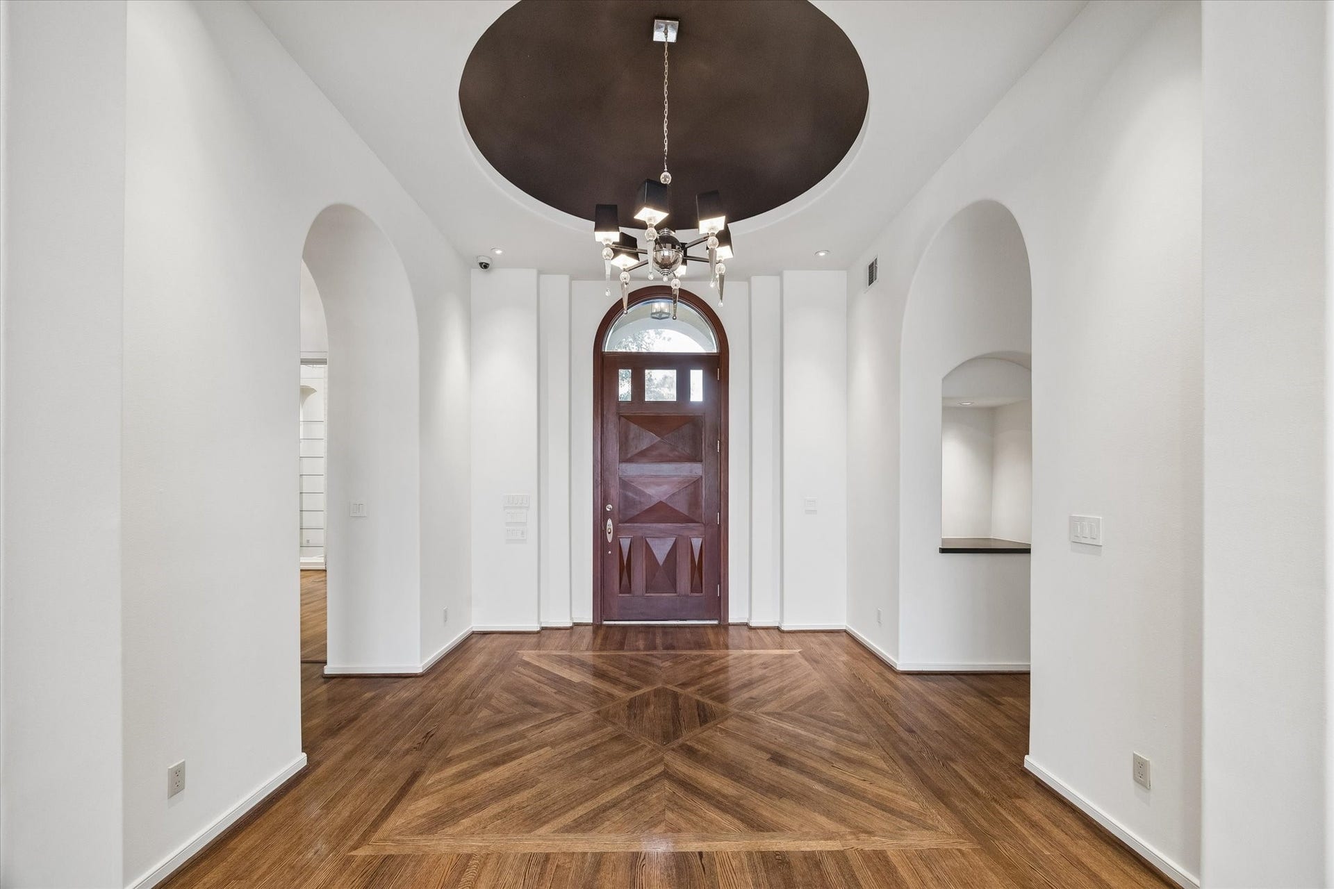 DRAMATIC FOYER WITH DOMED CEILING - accented with elegant lighting fixture, cove lighting in the dome, dual lighted art niches, beautiful hardwood flooring with inlaid design - note the arched entry and arches featured throughout this fine home