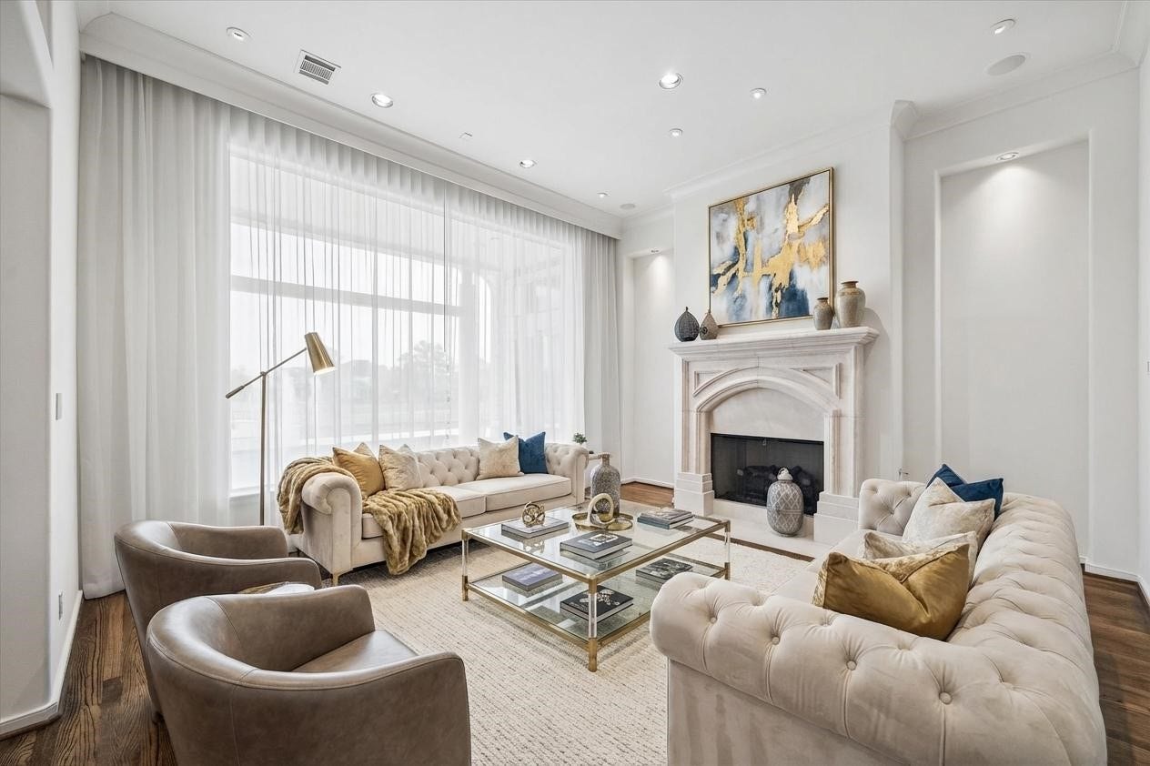VIRTUALY STAGED - formal living room with high ceiling, dual lighted art niches, gas-log fireplace - sheer draperies framing the large window with views of covered terrace and on to the pool/spa and lake