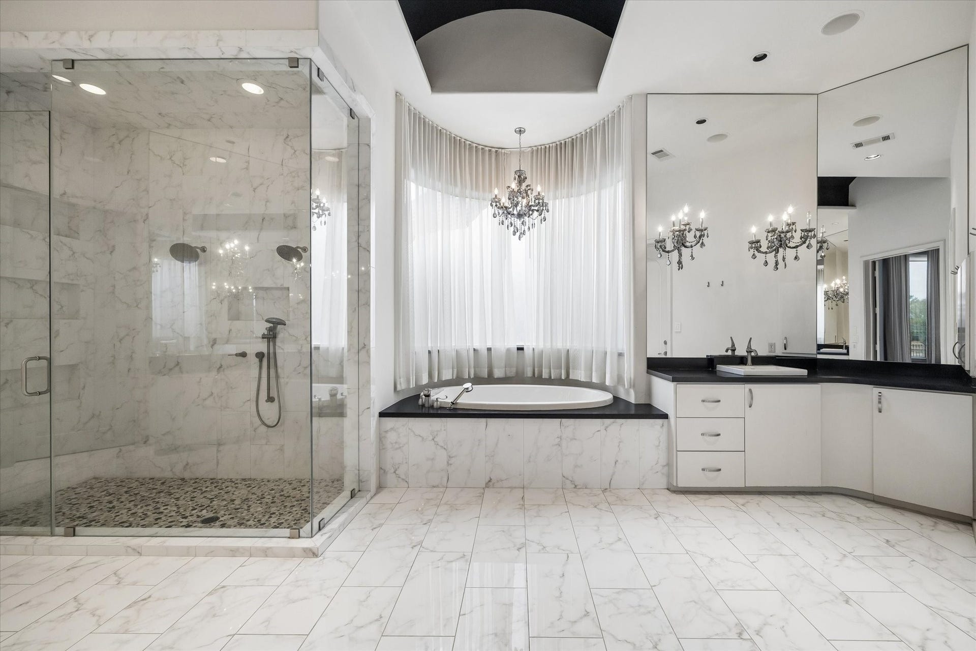 ELEGANT 'SPA-LIKE' ENSUITE PRIMARY BATHROOM WITH JETTED TUB AND OVERSIZE SHOWER - note the chandelier over the bath tub and dramatic arched ceiling, one of two vanity areas and access to one of the spacious walk-in closets