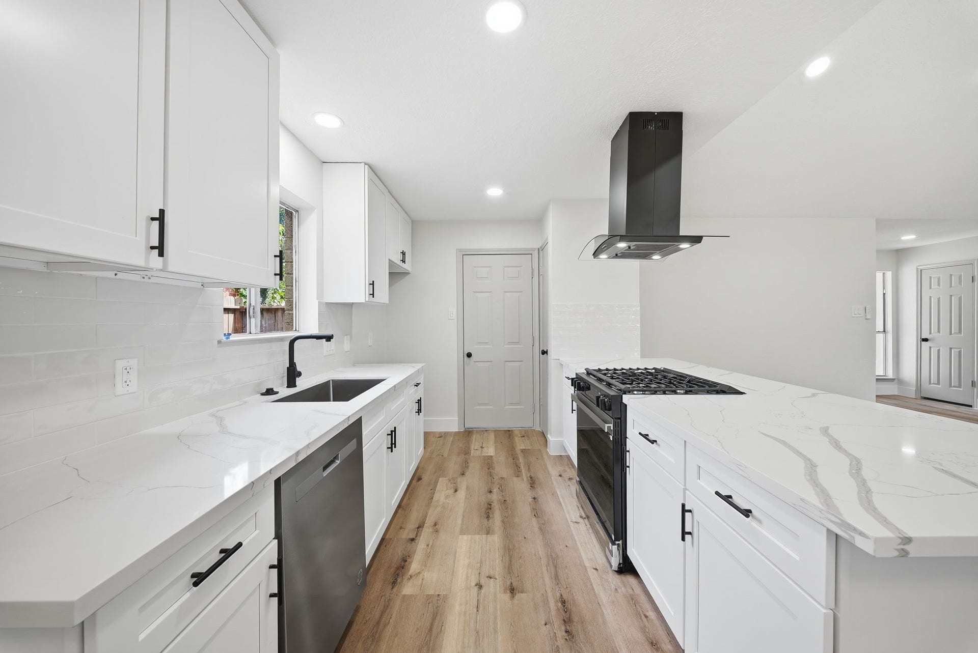 3816 Youpon Drive, La Porte, TX 77571 The kitchen features modern appliances, sleek white cabinetry, and elegant quartz countertops. Large windows above the sink invite the beauty of the outdoors inside.