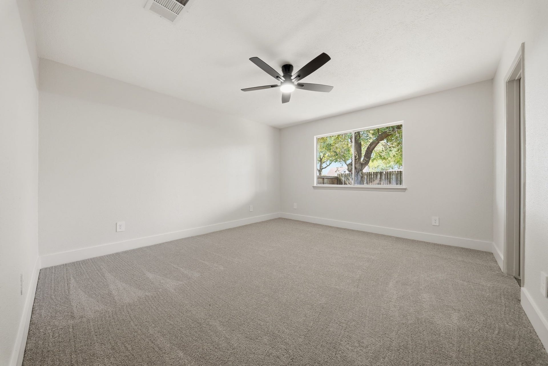 3816 Youpon Drive, La Porte, TX 77571 Spacious bedroom with plush carpeting, a large window offering natural light, and a modern ceiling fan for comfort.