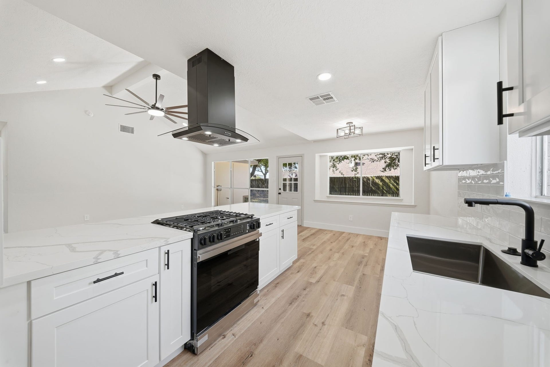 3816 Youpon Drive, La Porte, TX 77571 Sleek kitchen with modern gas burner stove with range appliances, seamlessly opening into a bright living area with large windows and stylish light fixtures.