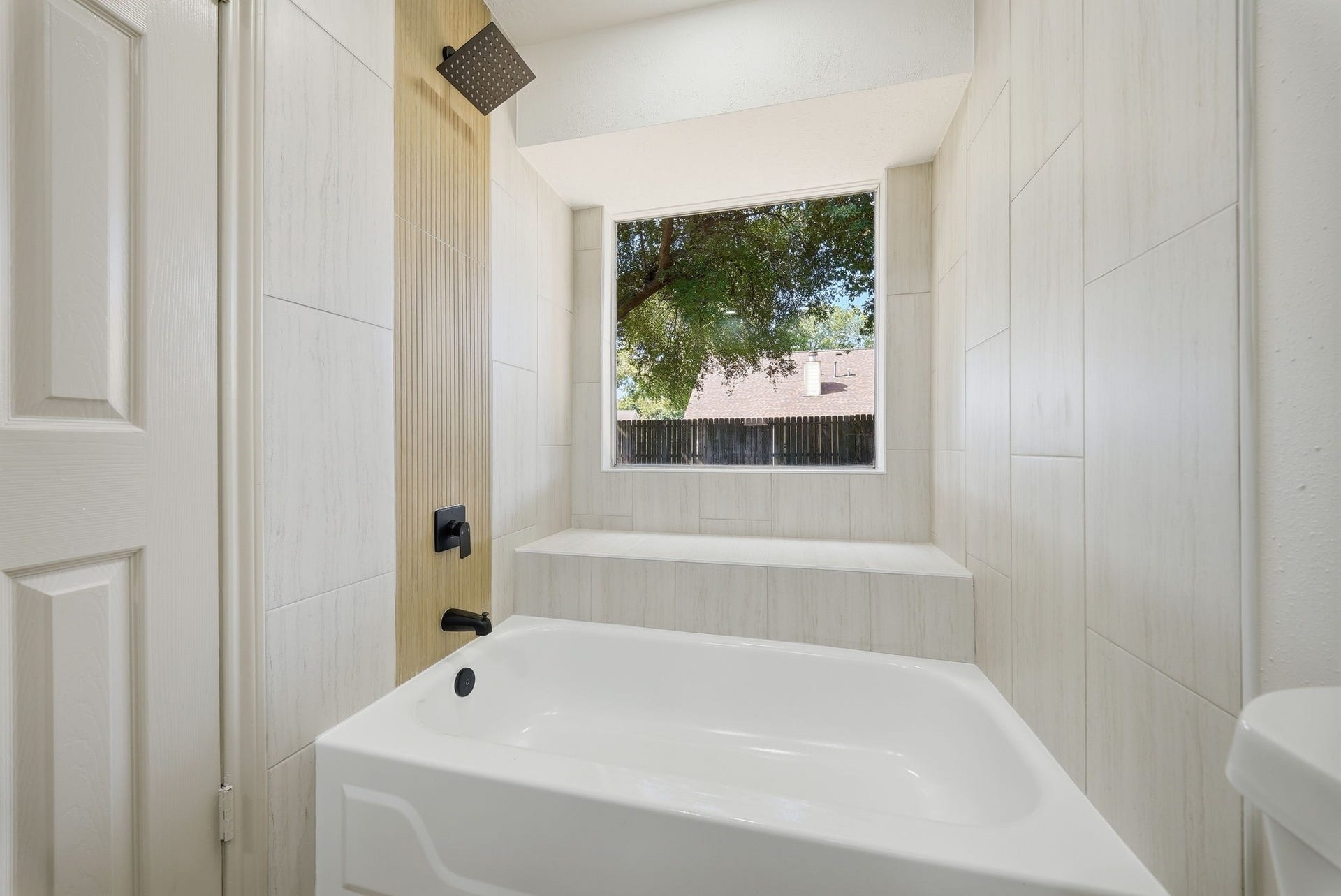 3816 Youpon Drive, La Porte, TX 77571 Inviting bathroom featuring a modern soaking tub and a large window and seat, providing natural light and a serene view.